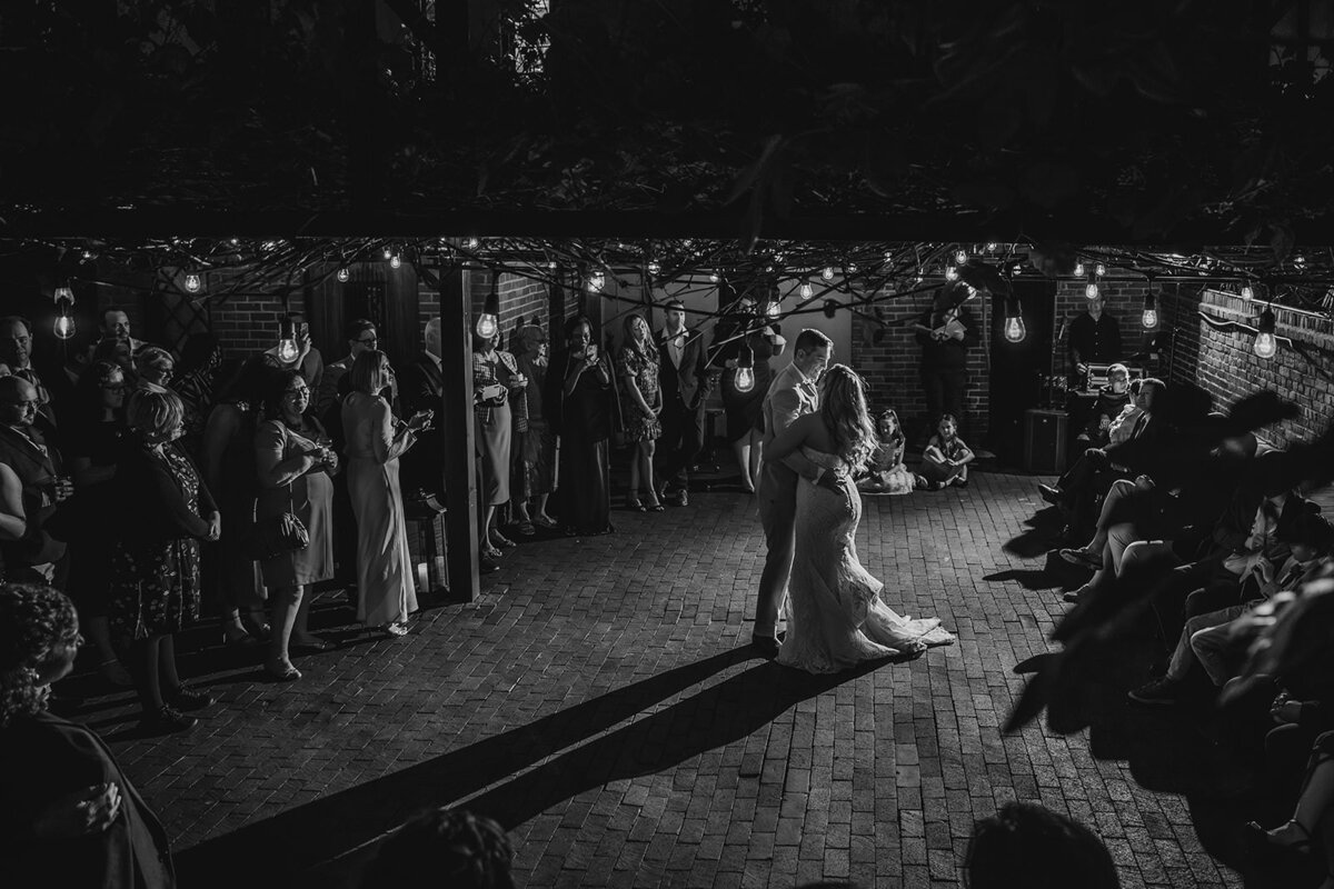 A wedding couple during their first dance as their guests watch 
