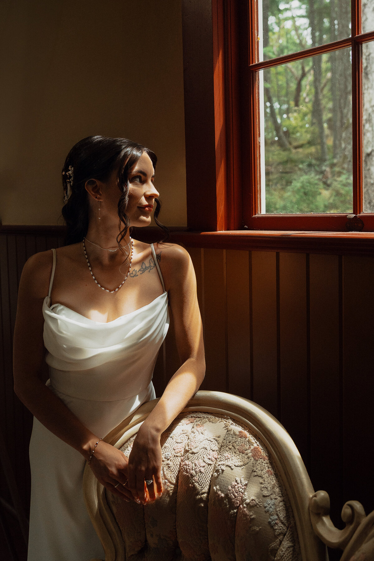 Bride looking out the window during her getting ready wedding portraits at Caleb Pike Heritage Park in Victoria by Latitude 49 Photography