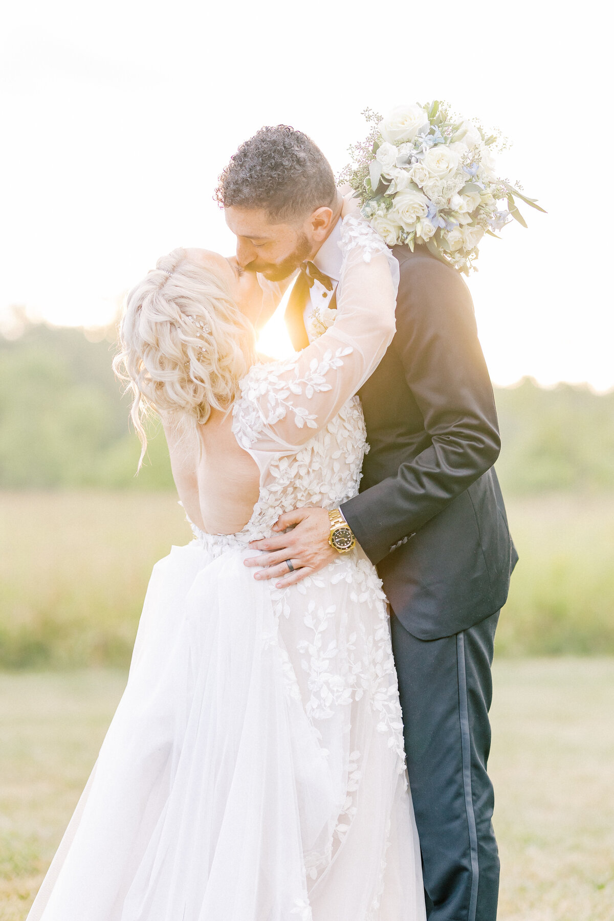 Sunset portrait of a couple kissing on their wedding day.