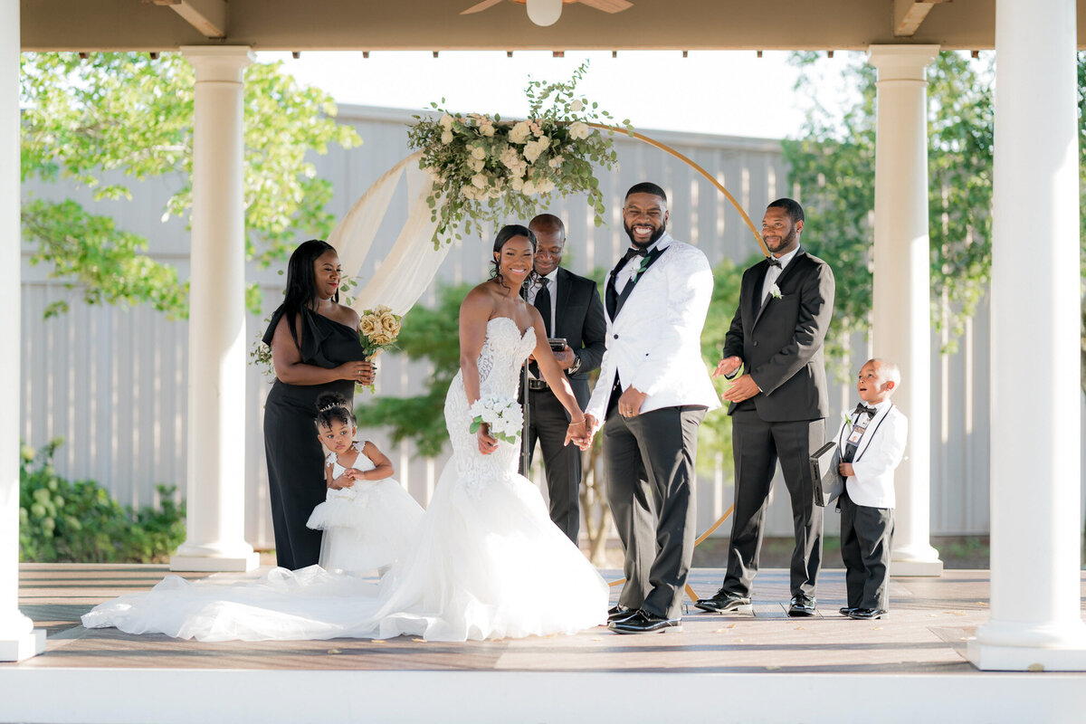 Bride and groom holding hands with entourage beside them