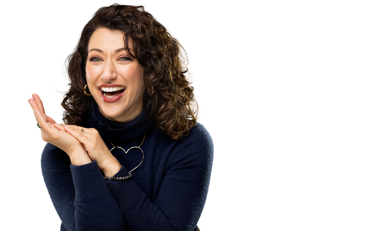 woman in blue shirt smiling at the camera with her hands together