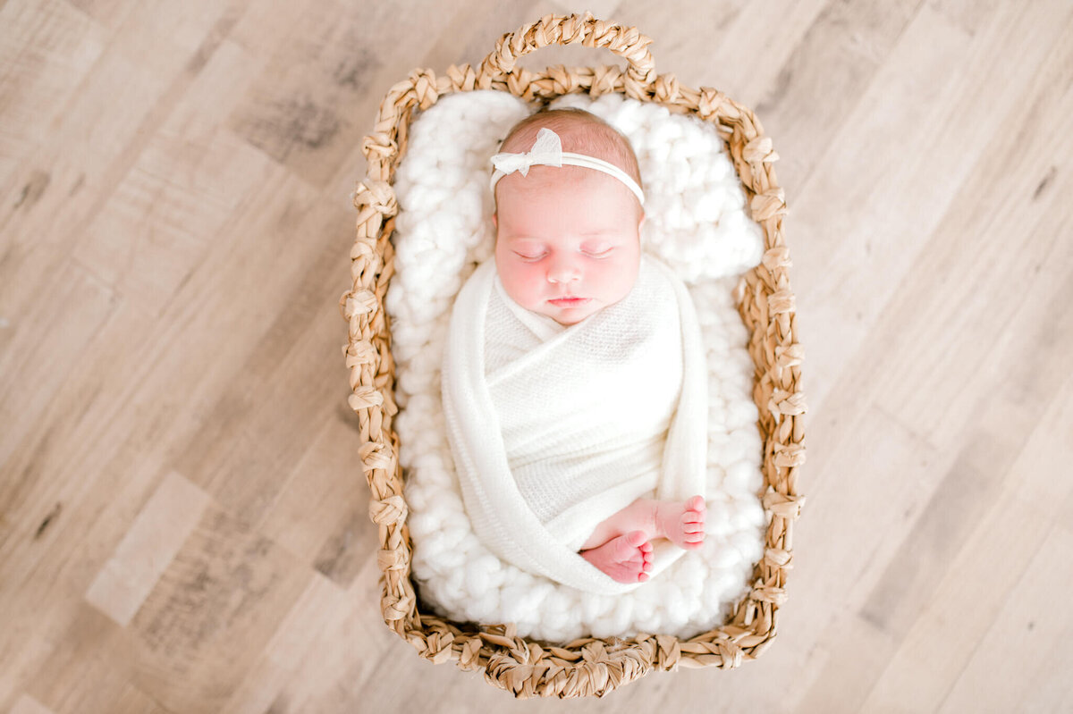 Newborn baby girl in a basket, wrapped in white