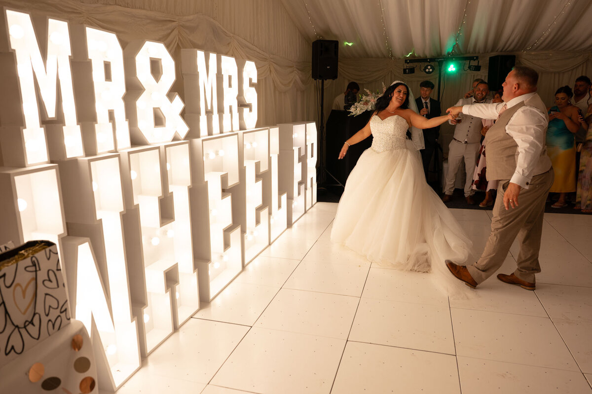Bride and groom first dance in front of Wedding Surname sign – Manchester wedding photography.
