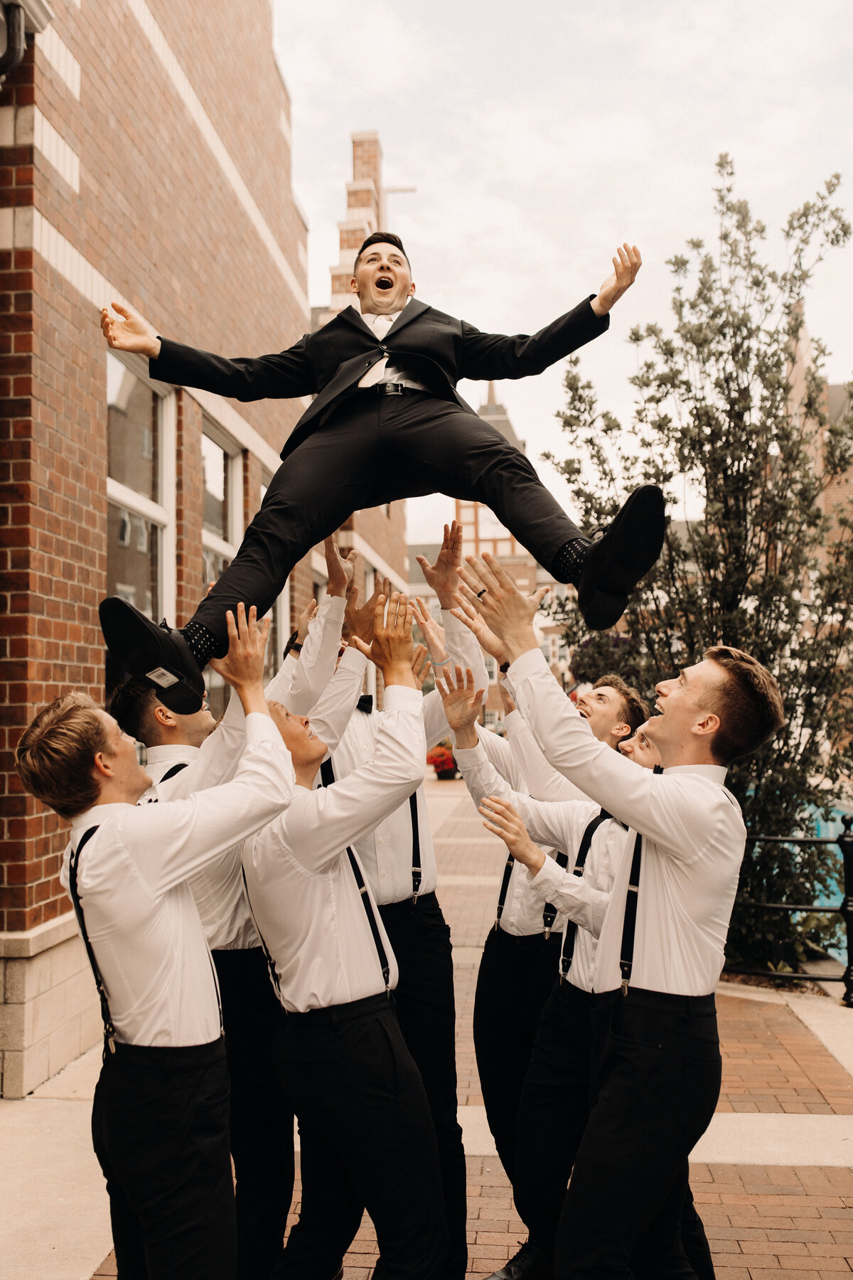 groomsmen throwing groom in the air at iowa wedding