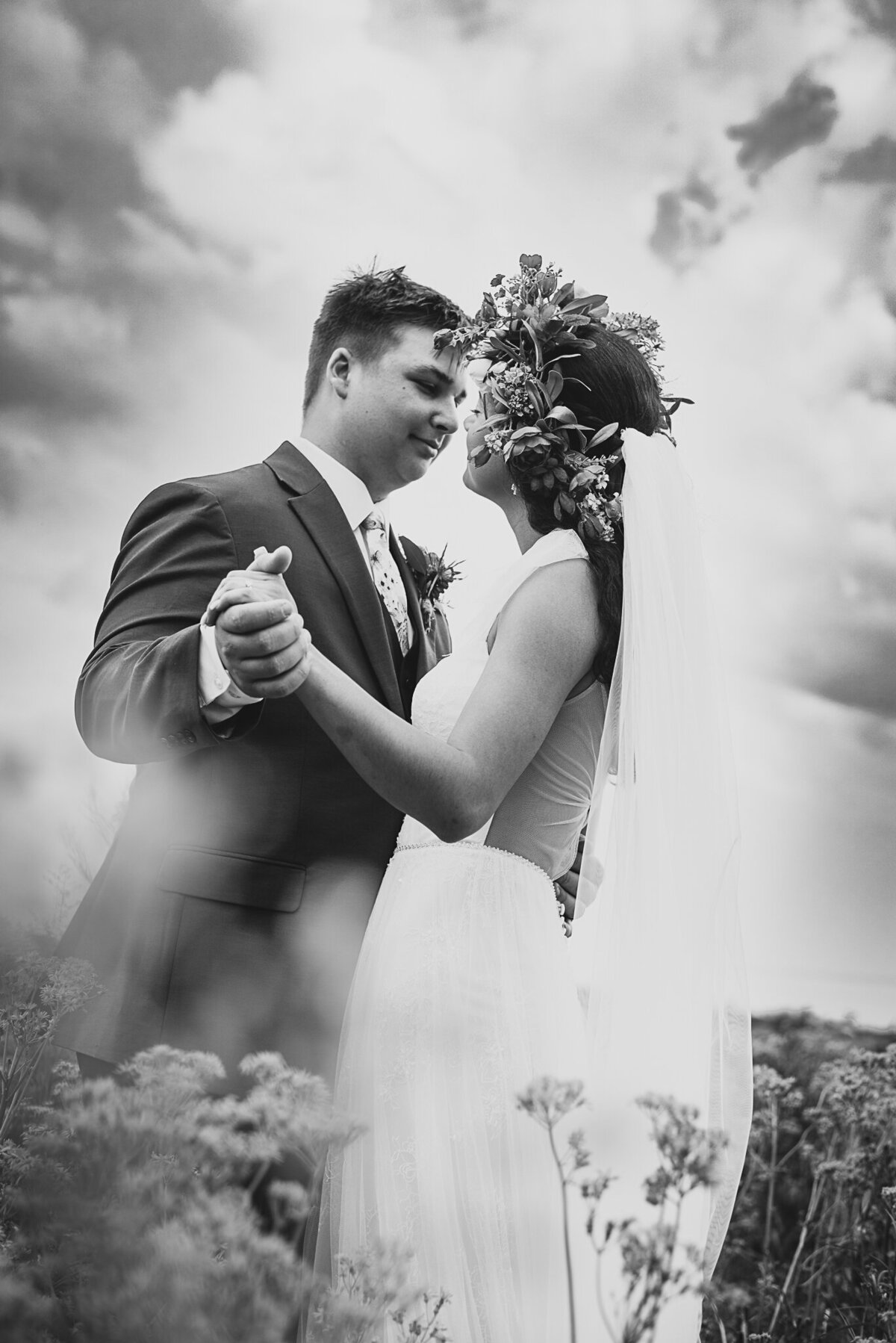 Bride and groom, Ronicia and Jack Henderson, dance together underneath clounds in a field of flowers in Xenia, Ohio.