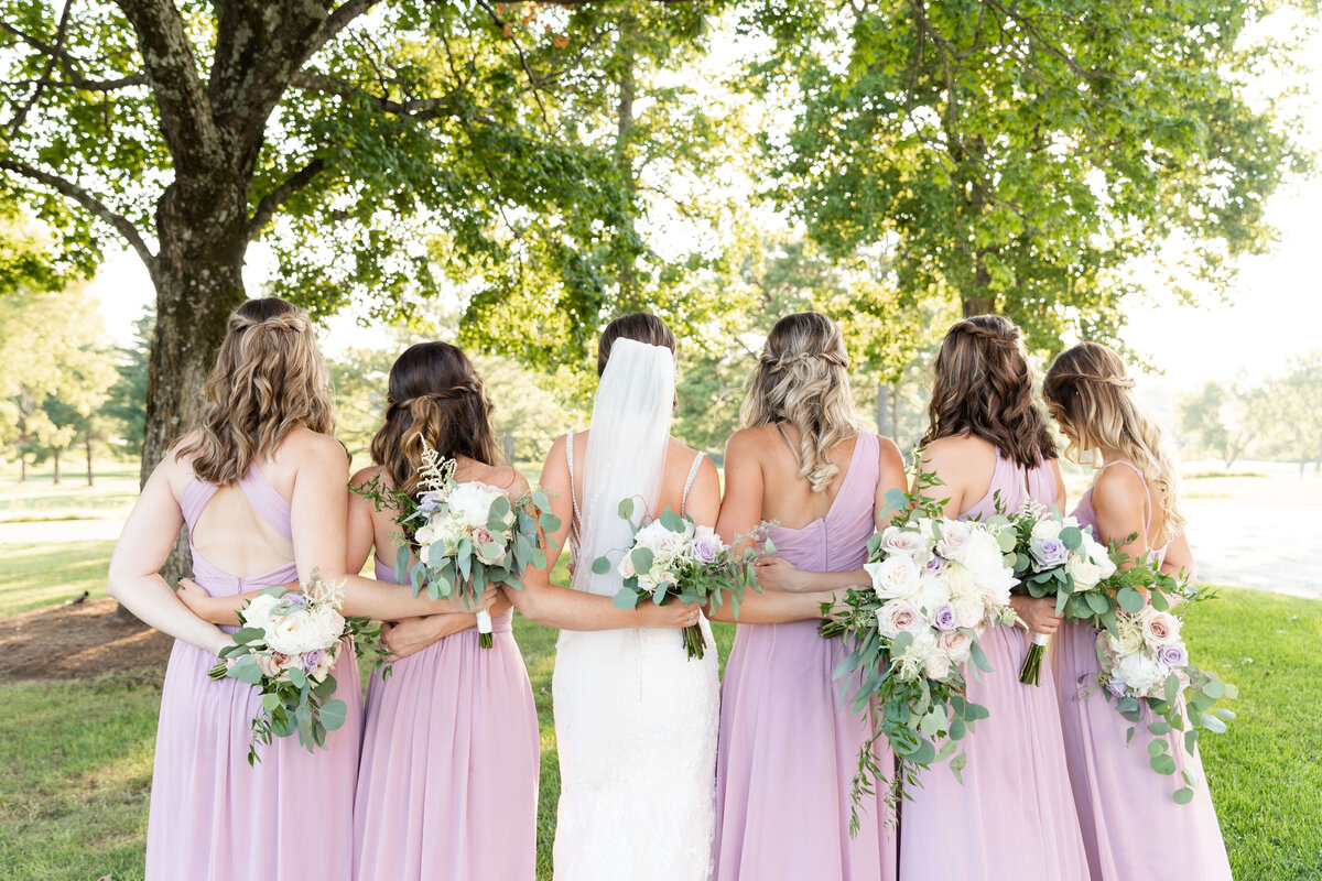 Bride with bridesmaids with backs to camera at wedding at Stones River Country Club