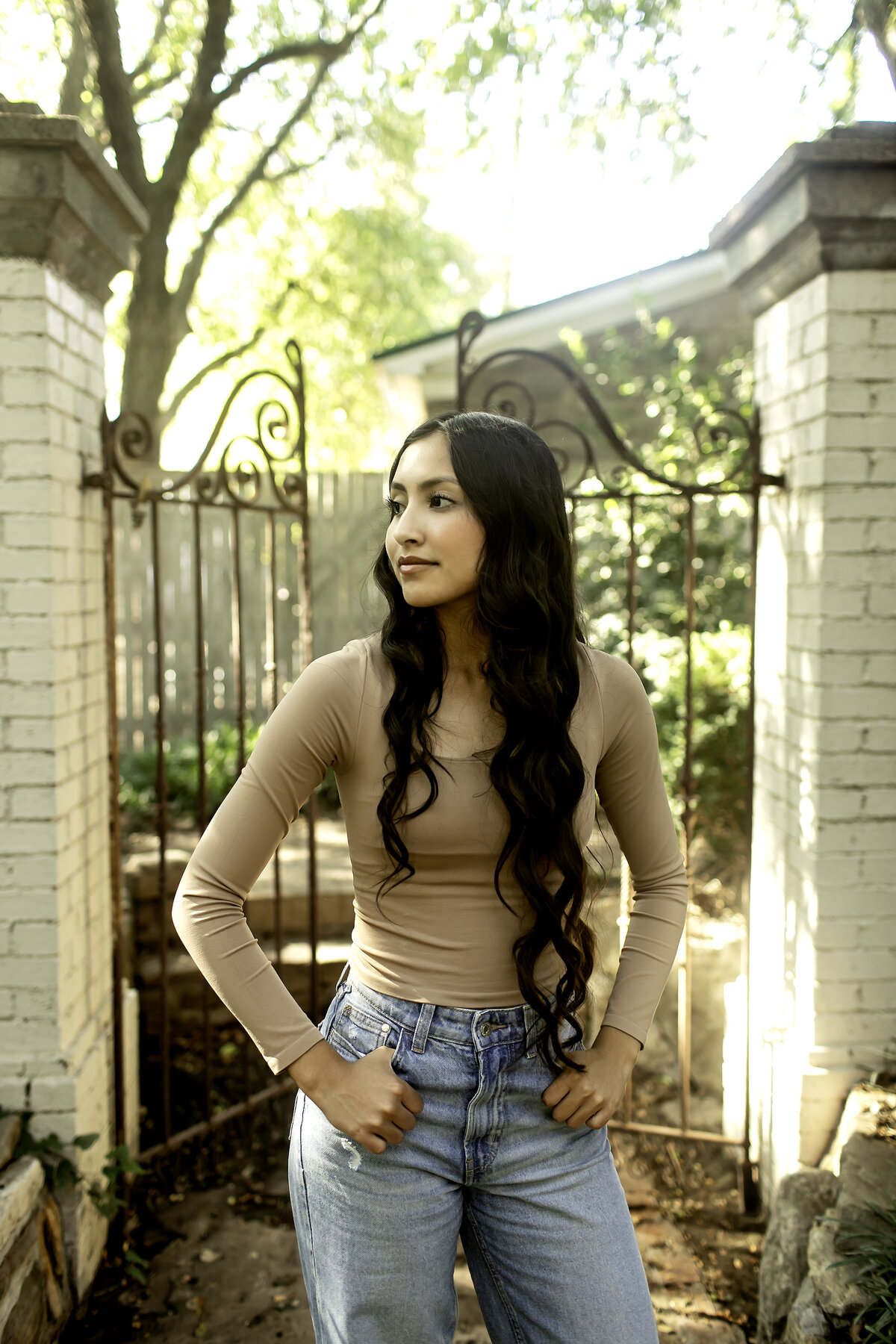 A high school senior posing gracefully amidst the lush greenery and vibrant flowers of Chandor Gardens in Weatherford, TX, capturing the beauty of nature and the excitement of graduation