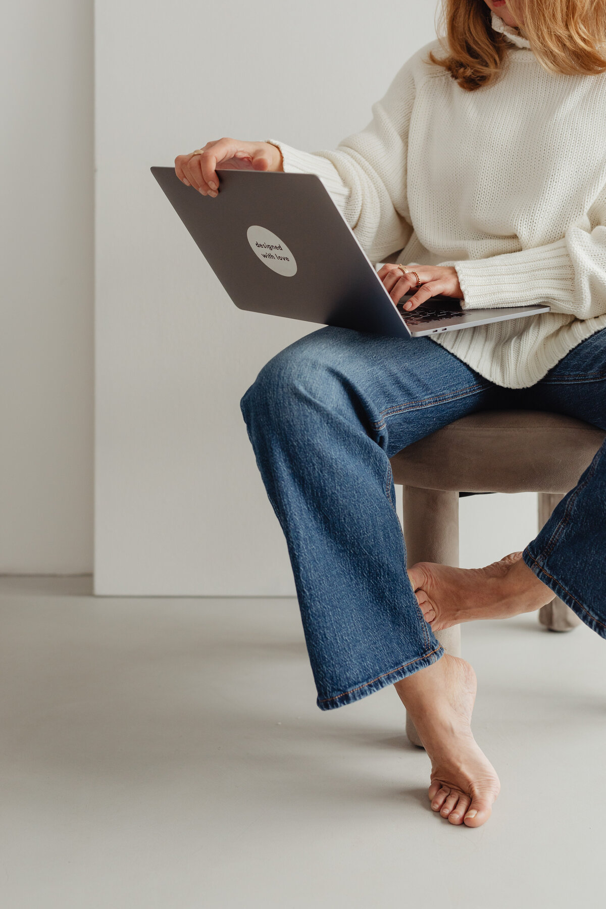 kaboompics_woman-in-white-sweater-gold-rings-jewelry-jeans-laptop-work-29449