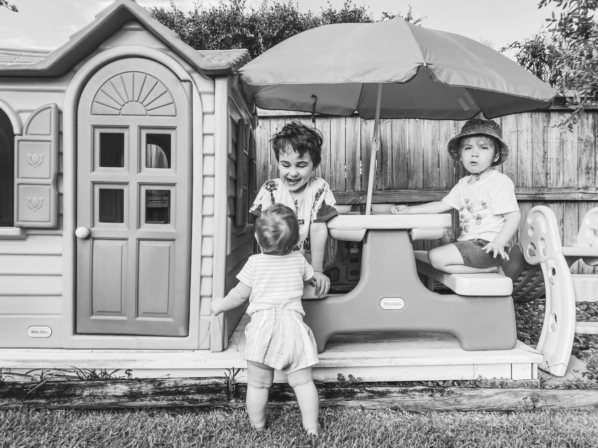 Three children playing with a cubby house
