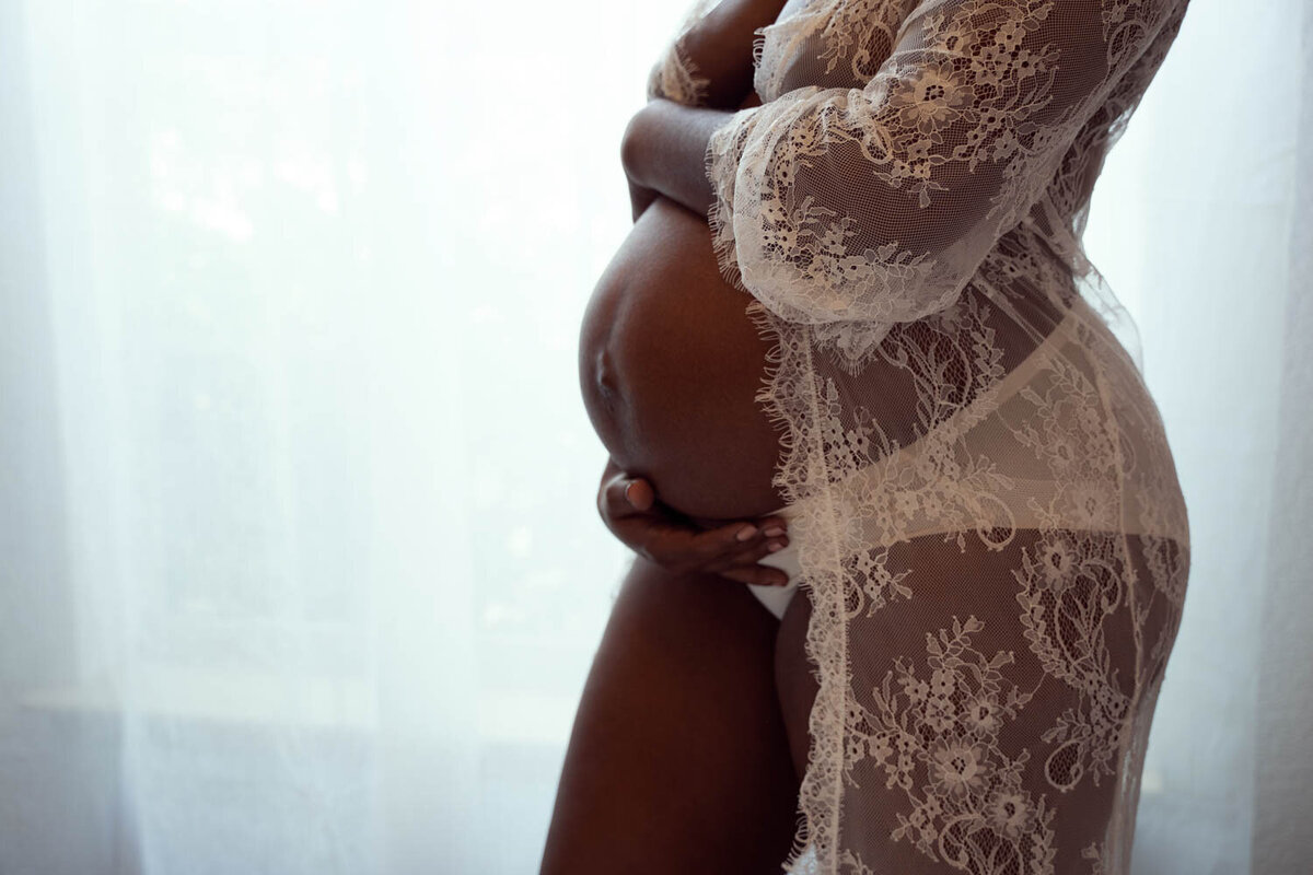 A Woman holding her baby belly in her boudoir photo session