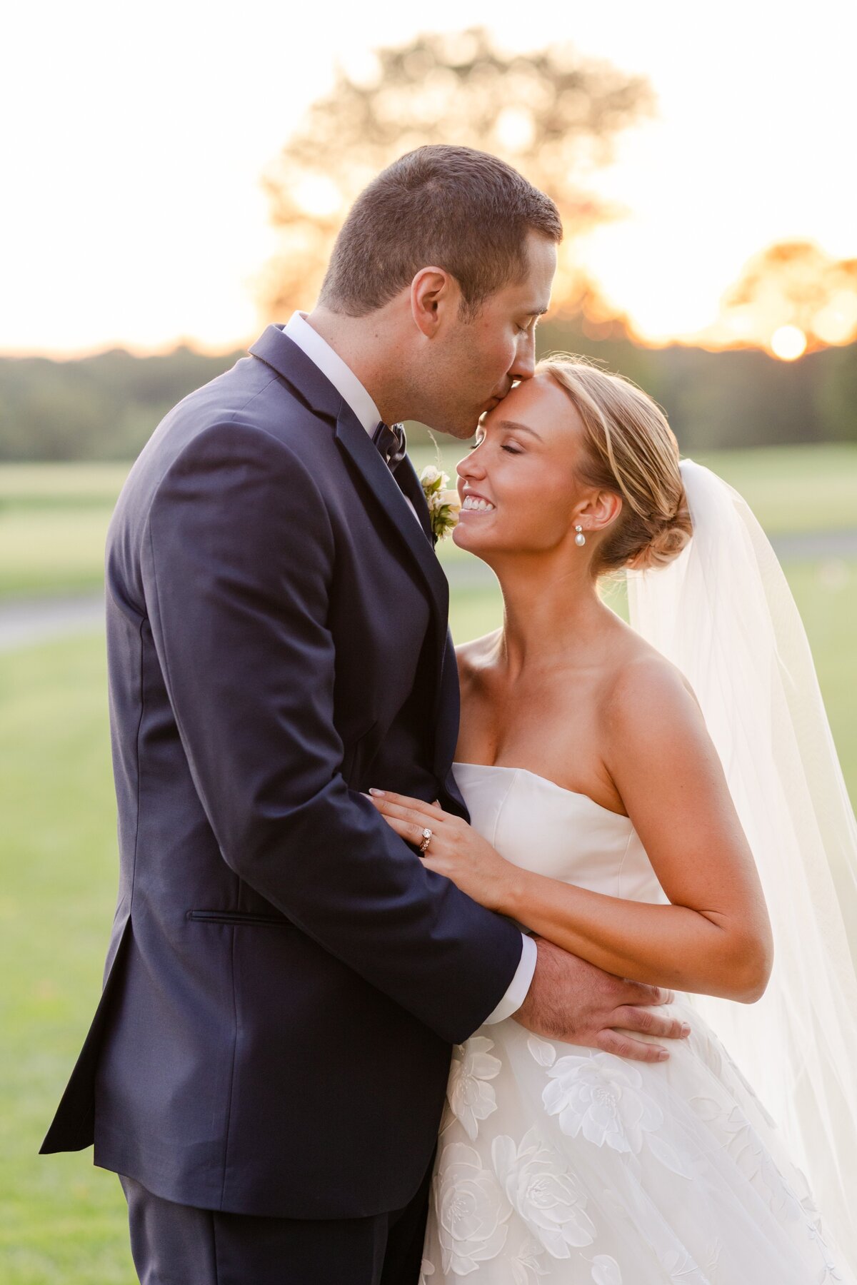 groom kissing bride on forehead on the golf course at Westchester Country Club