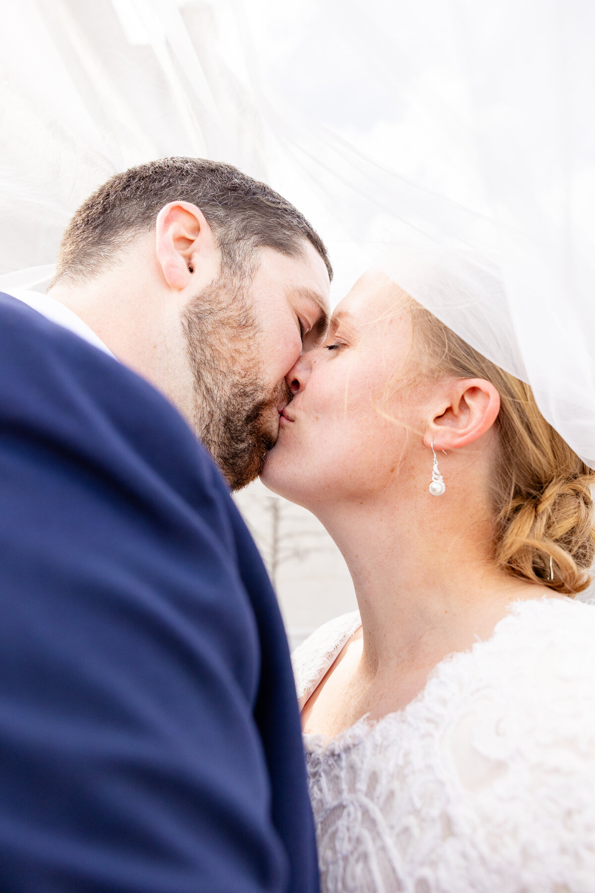 Close-up of bride and groom sharing a romantic kiss beneath the bride's veil at the Taylorsville Utah Temple. Taken by Cassie Lee Photography.