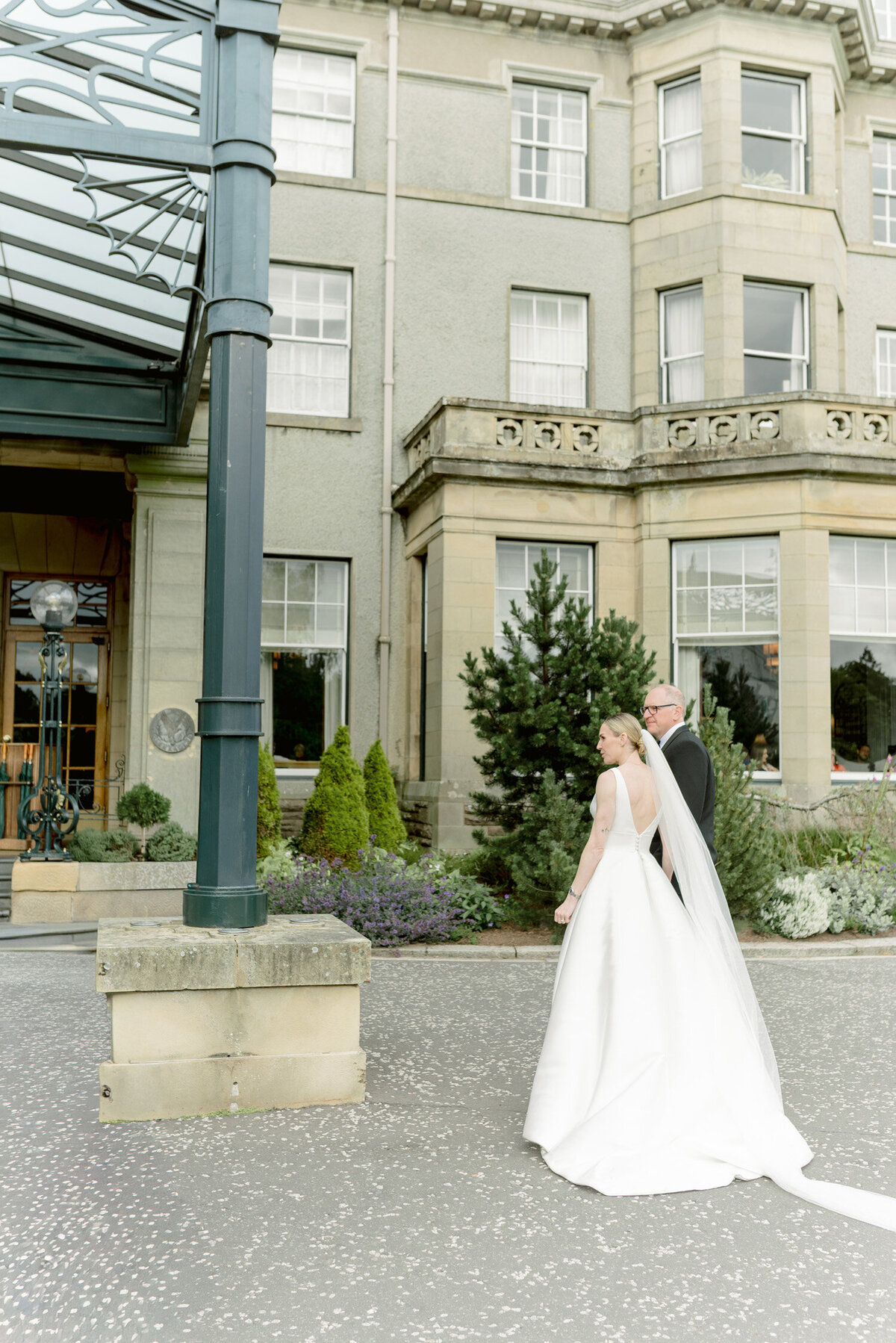 Bride and Groom arrive at the entrance of Gleneagles Hotel on their wedding day. Image by luxury wedding photographer uk, Jill Cherry Porter.