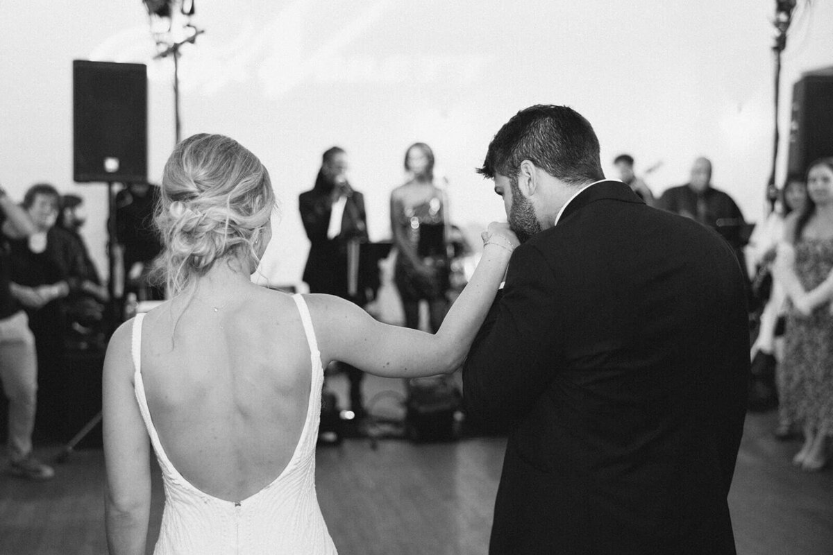 Groom kissing brides hand at wedding reception