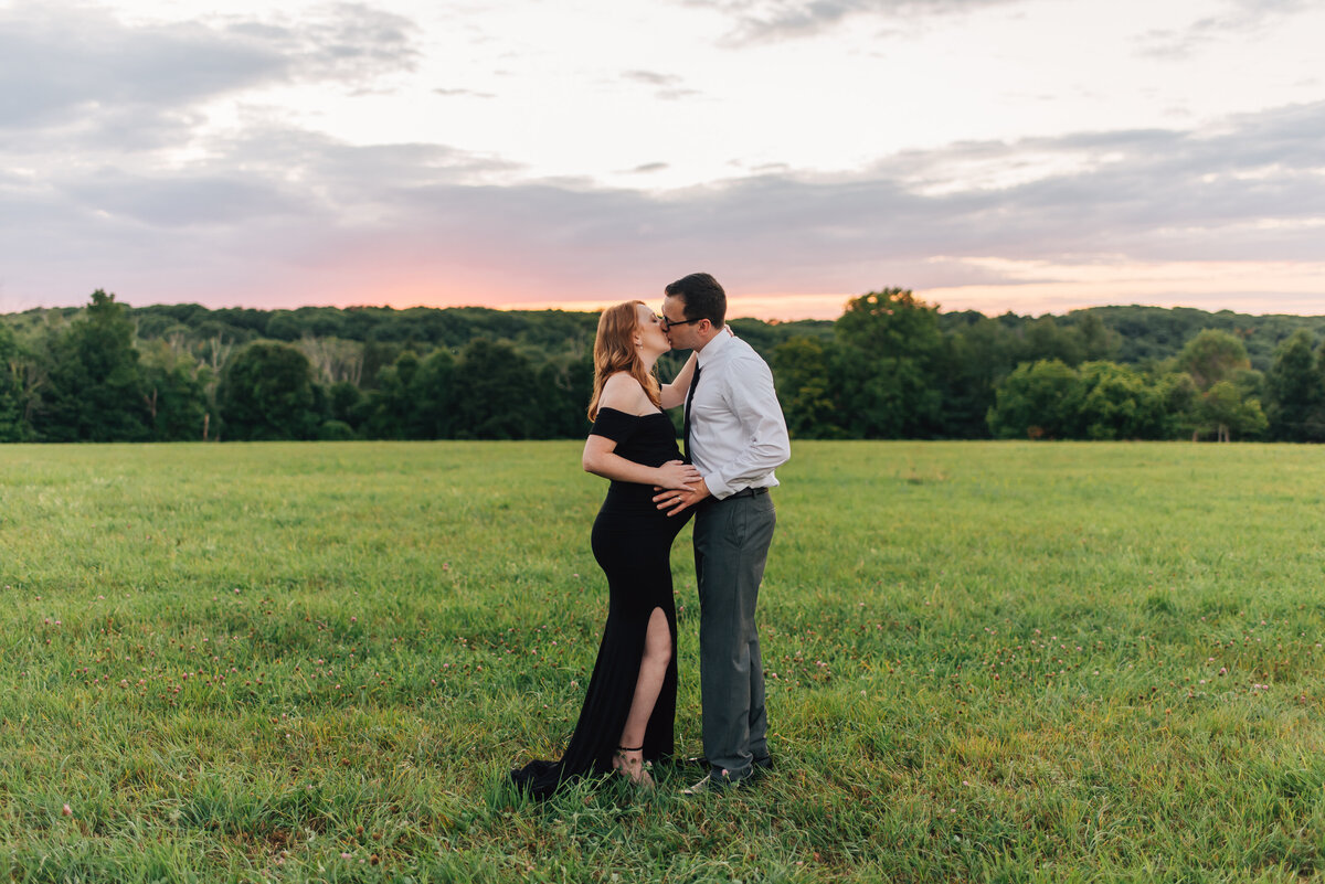 Couple kissing in field at sunset