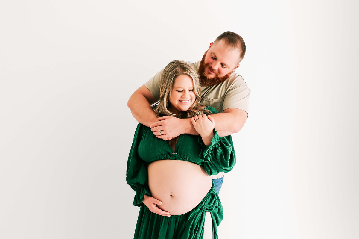 Springfield MO matenrity photographer Jessica Kennedy of The XO Photography captures husband hugging pregnant wife from behind smiling