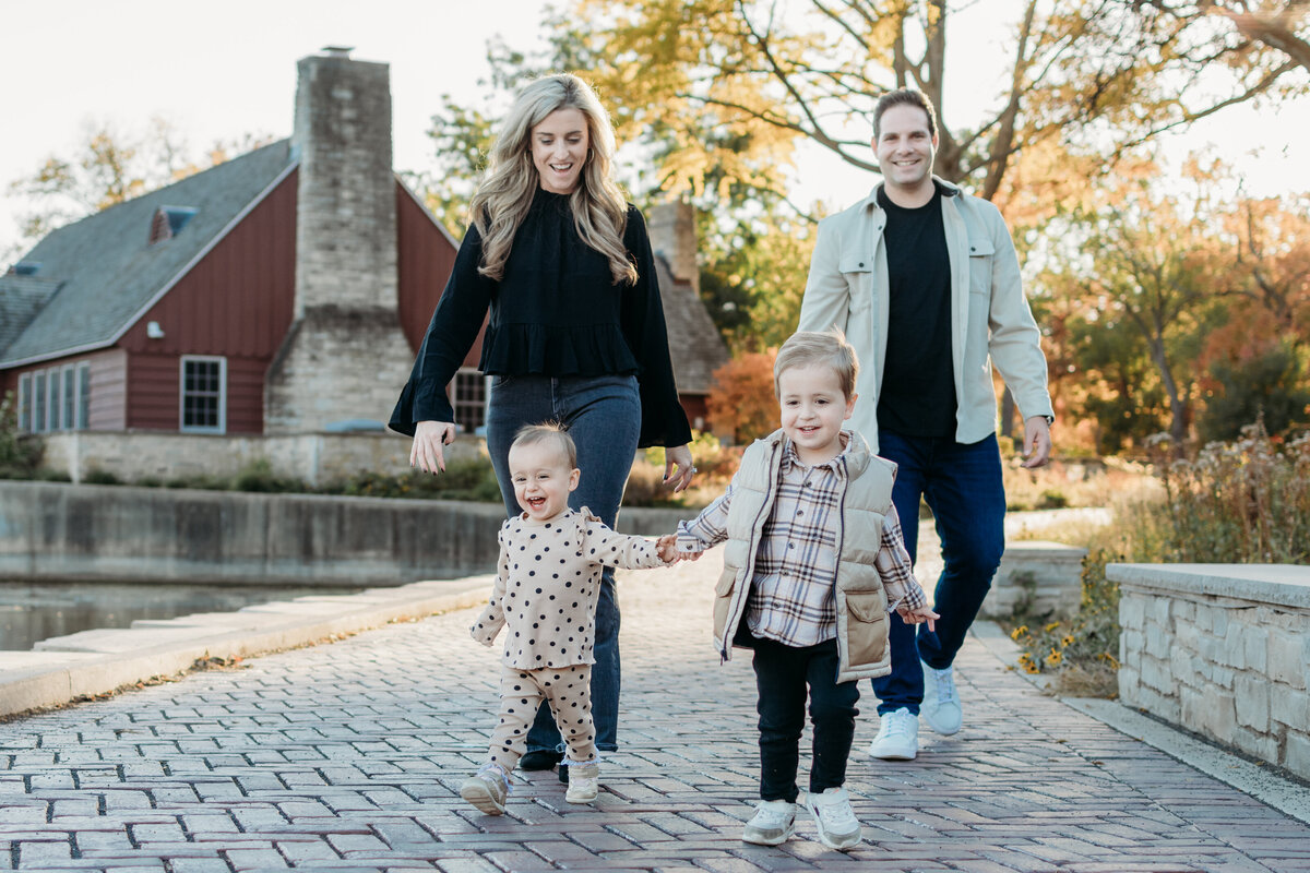 Toddlers leading their parents in a run during a family photoshoot near Lake Ellyn, IL