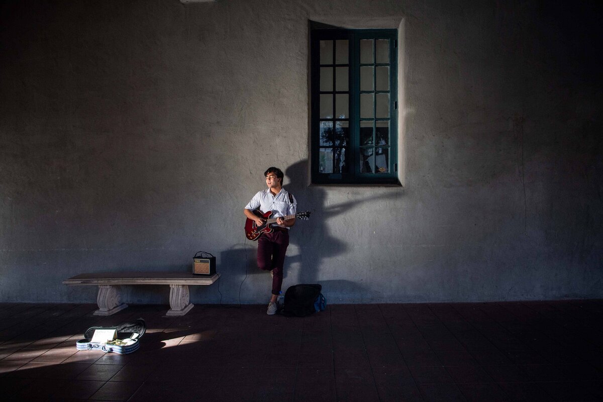 A guitarist lit by dramatic light as he plays in Balboa Park