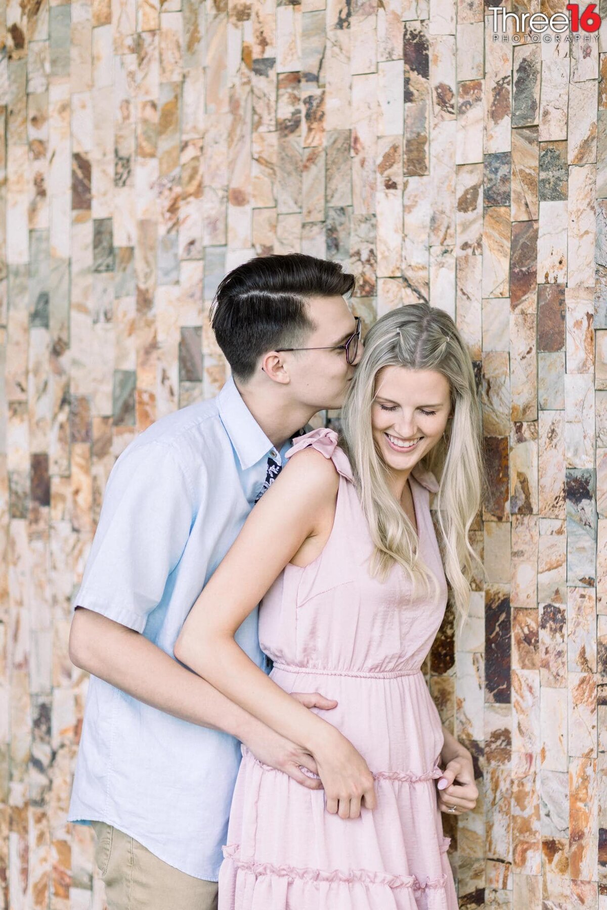 Groom to be whispers in his Bride's ear causing her to laugh