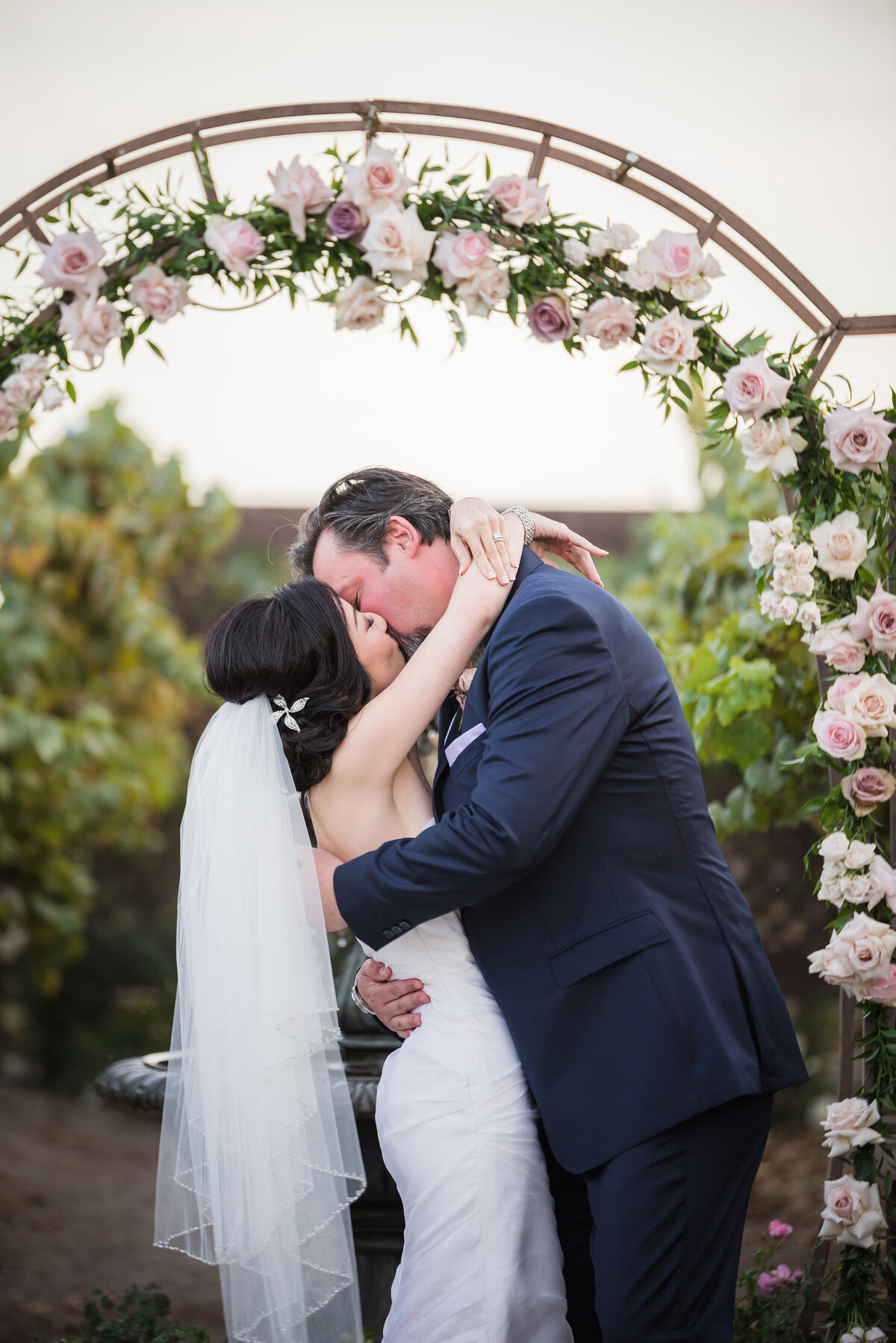 pink rose arch with bride and groom