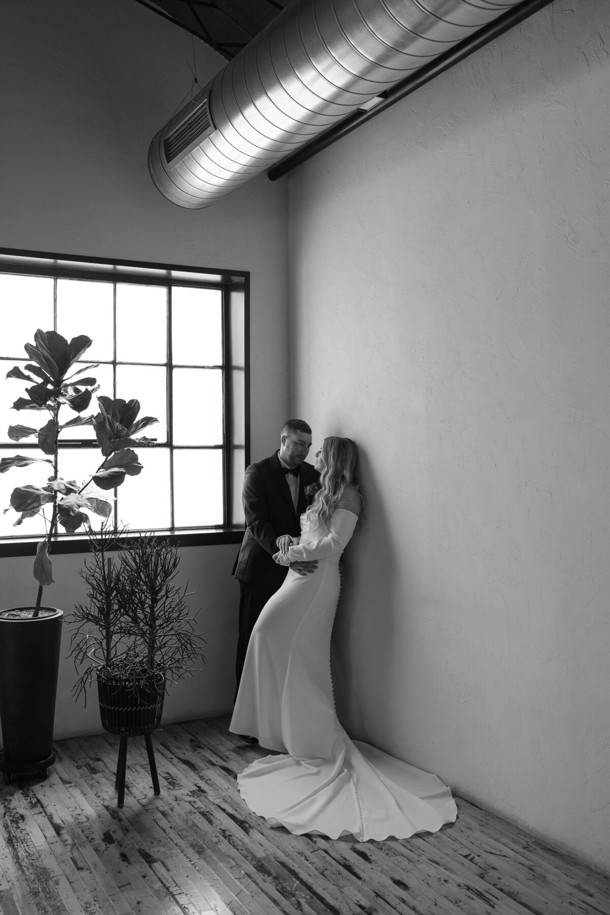 Romantic portrait of the couple in The Tinsmith's greenhouse space, surrounded by lush greenery and industrial charm.
