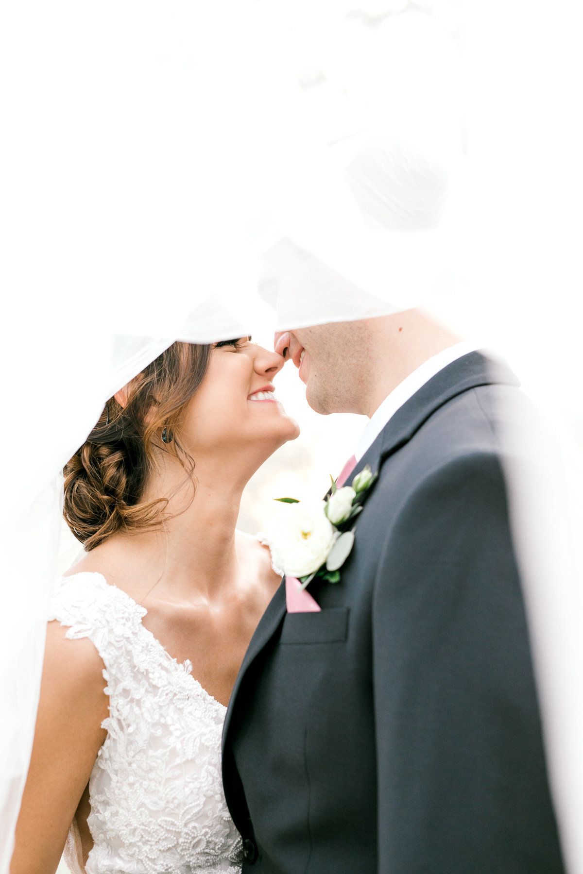 couple smiling under wedding veil