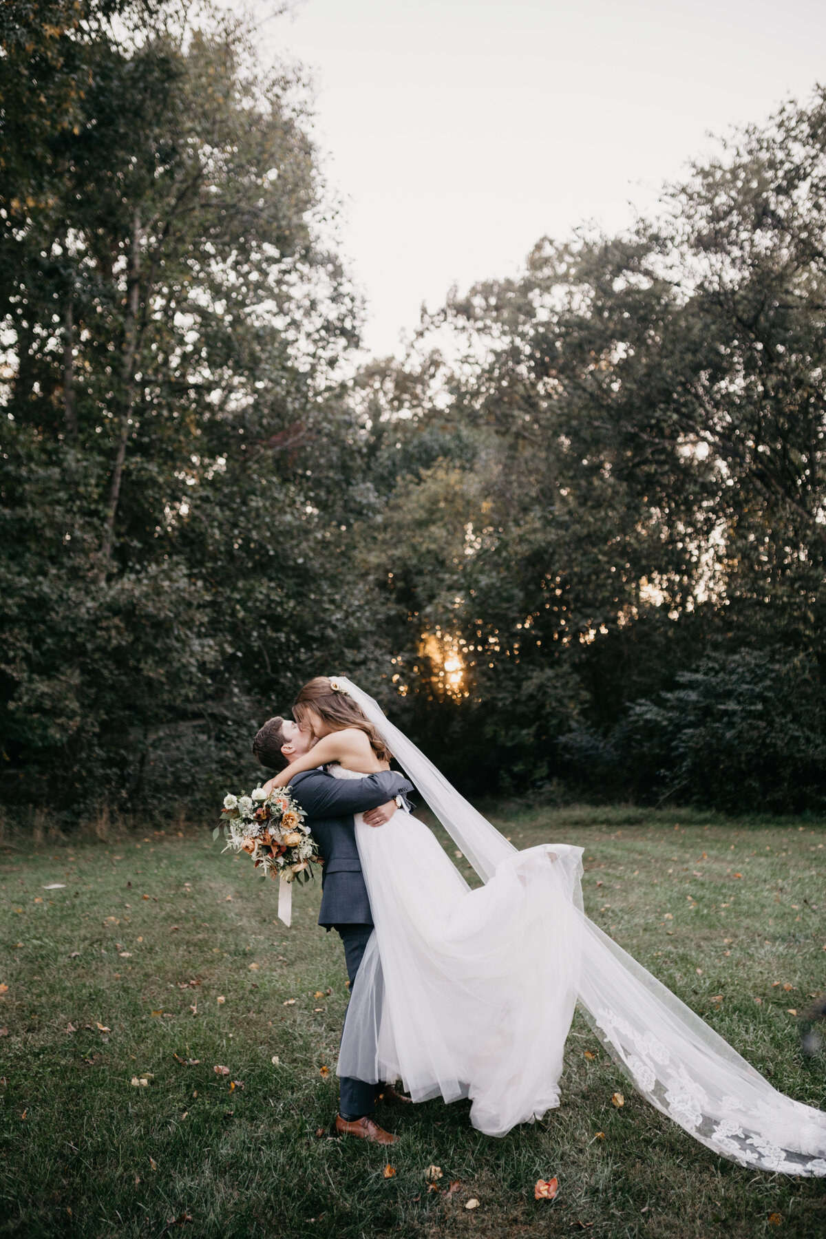 newlyweds kissing in field at golden hour