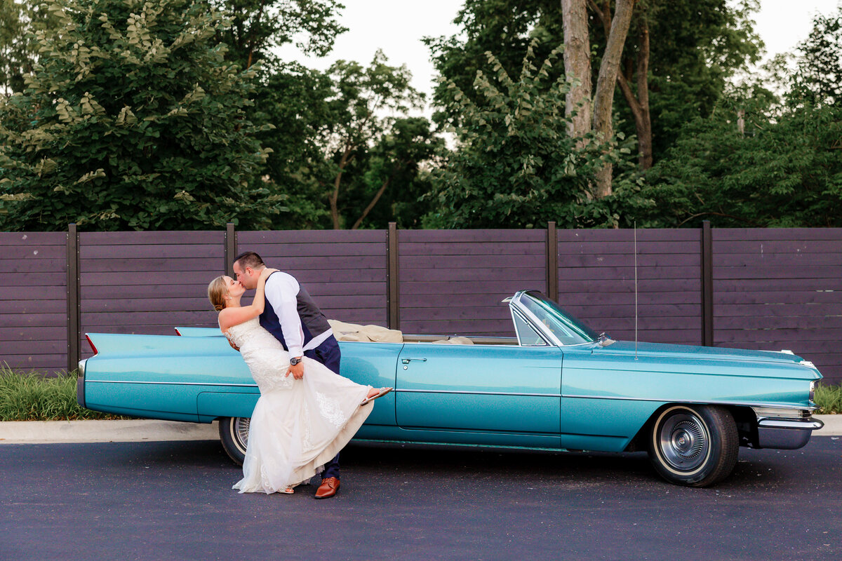 wedding couple share a kiss and a dip with their classic car.