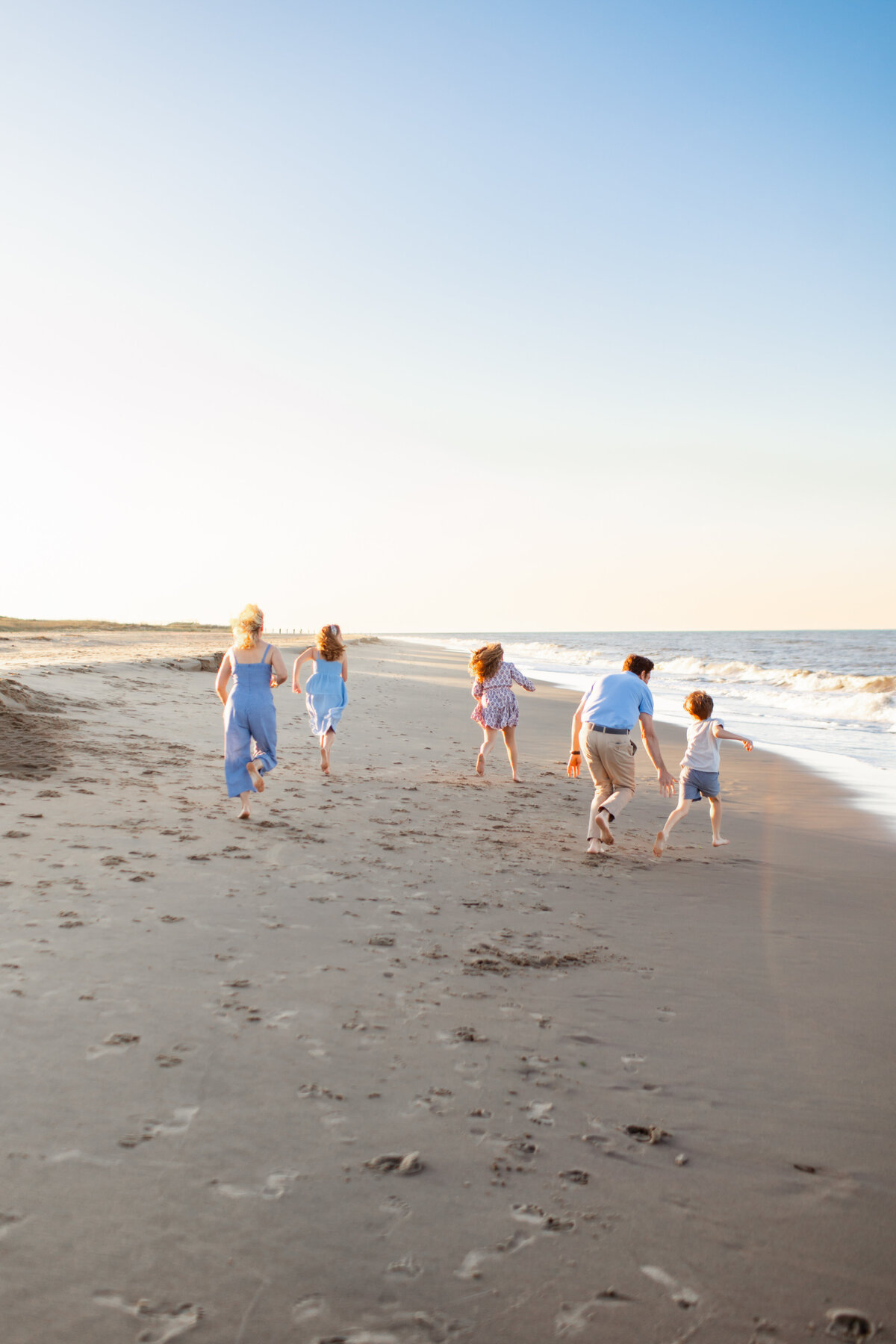 A joyful family running along the shore during a Virginia Beach photography session with Brooke Tucker