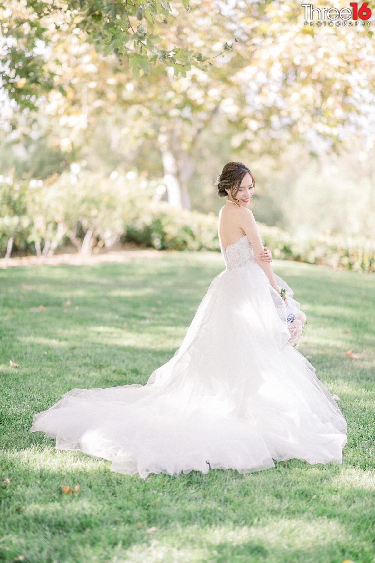 Beautiful Bride poses by looking down at her fanned out dress train