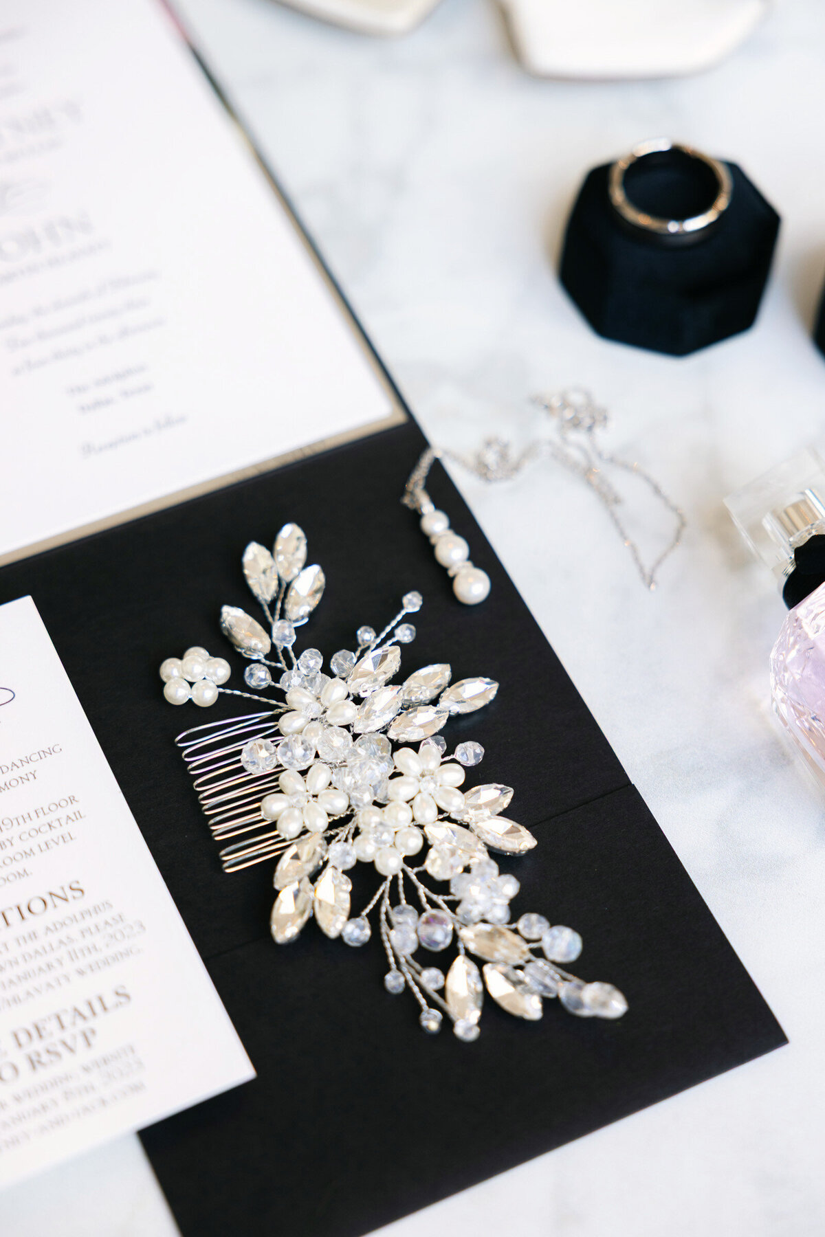 close up of a bridal hairpiece with beads and pearls placed on the wedding invitation at The Adolphus in Dallas, highlighting elegant wedding accessory details.