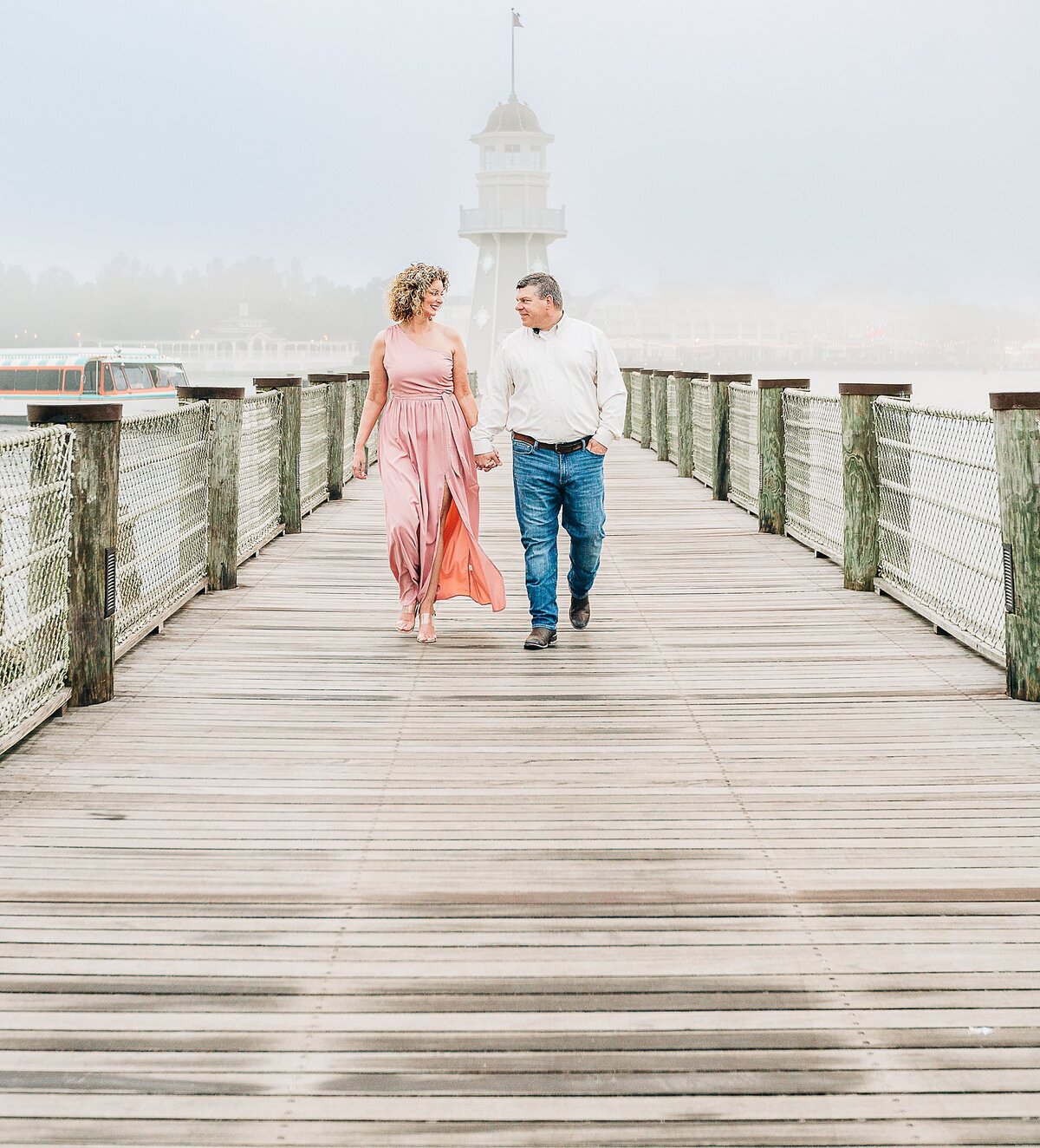 Couple walking on a bridge with fog, holding hands looking at each other in love