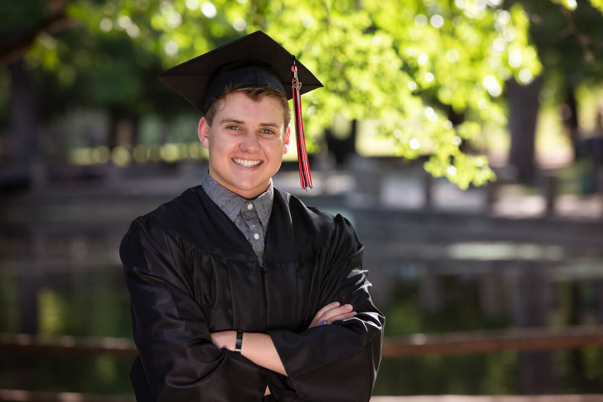 seniro-boy-posing-with-arms-crossed-in-cap-and-gown