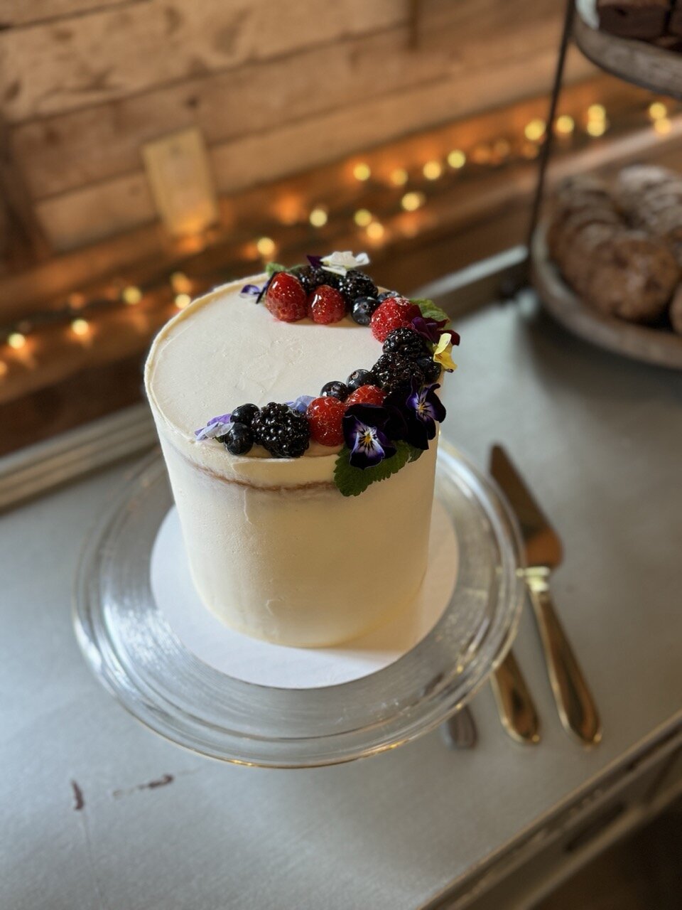 Elegant gluten-free cake decorated with fresh berries and minimalist buttercream design, made at Grain Artisan Bakery in Snohomish, Washington.