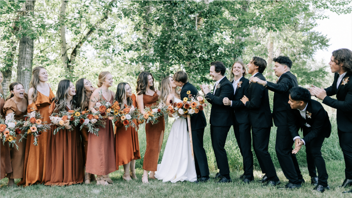 Bridal party celebrates as bride and groom kiss