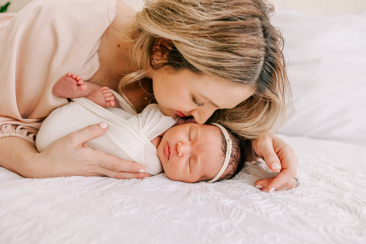 mom smelling baby's head for beautiful newborn portrait session in portland oregon