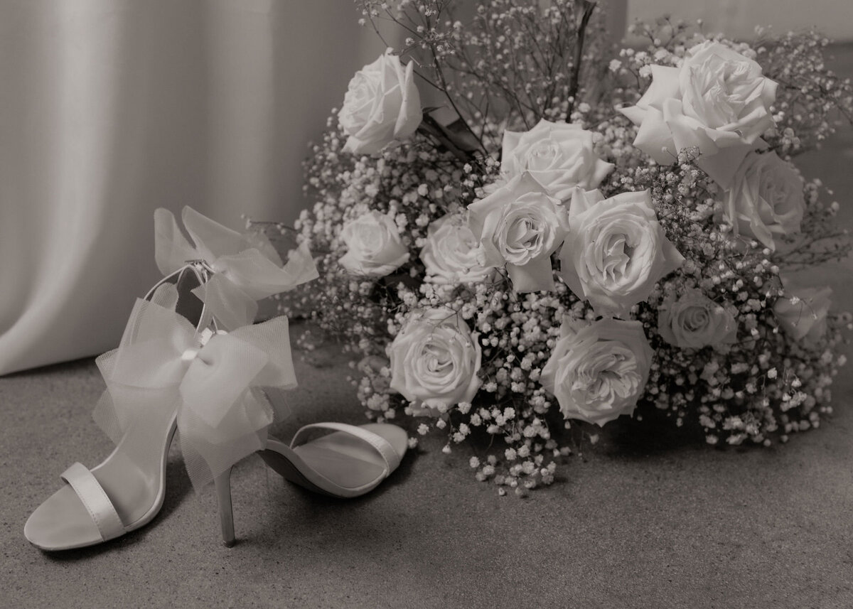 detail shot of rose and babies breath bouquet next to heels with bows on them