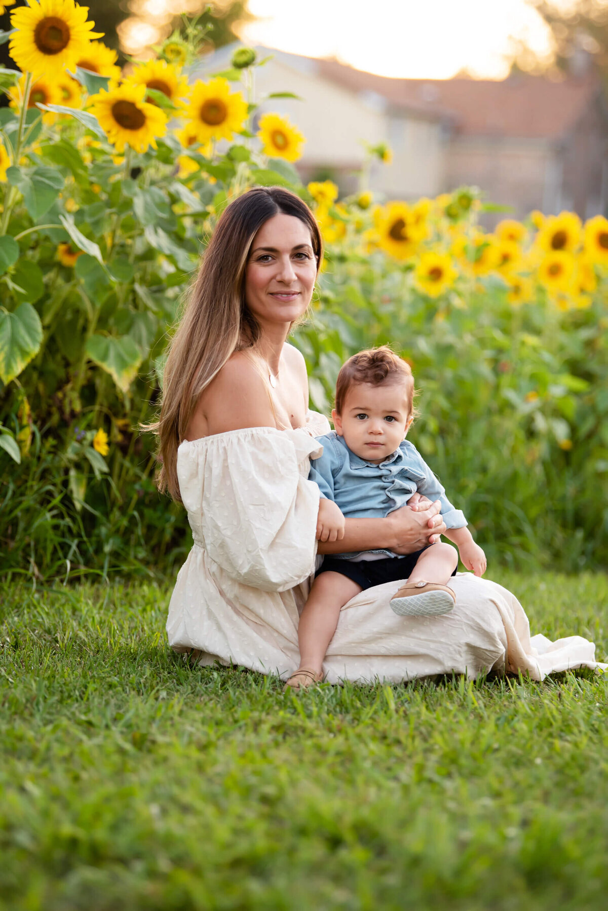 mom and son sitting on the ground in front of a sunflower field for their family photos Burlington, On