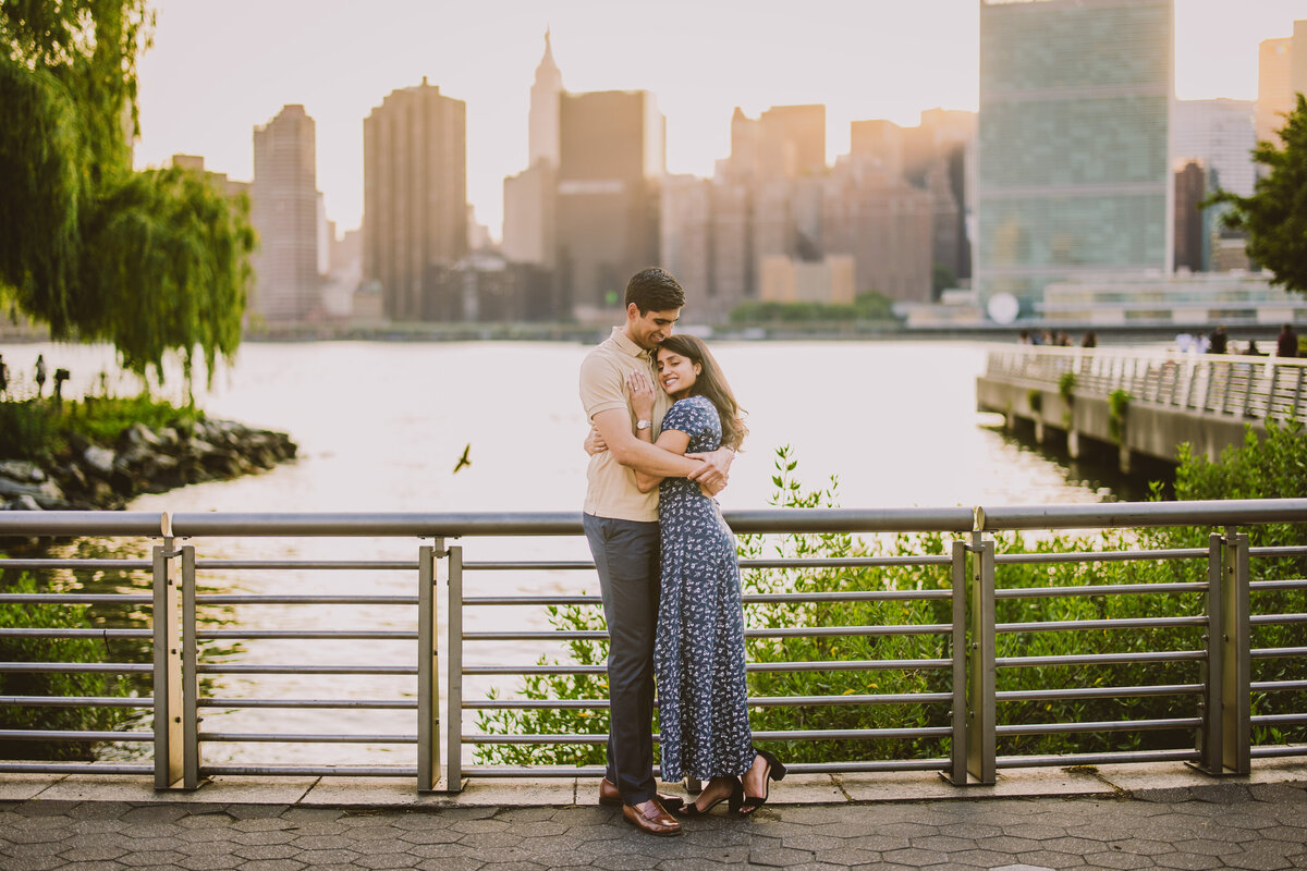 A couple embracing during their engagement session at the gantry plaza in long island city nyc