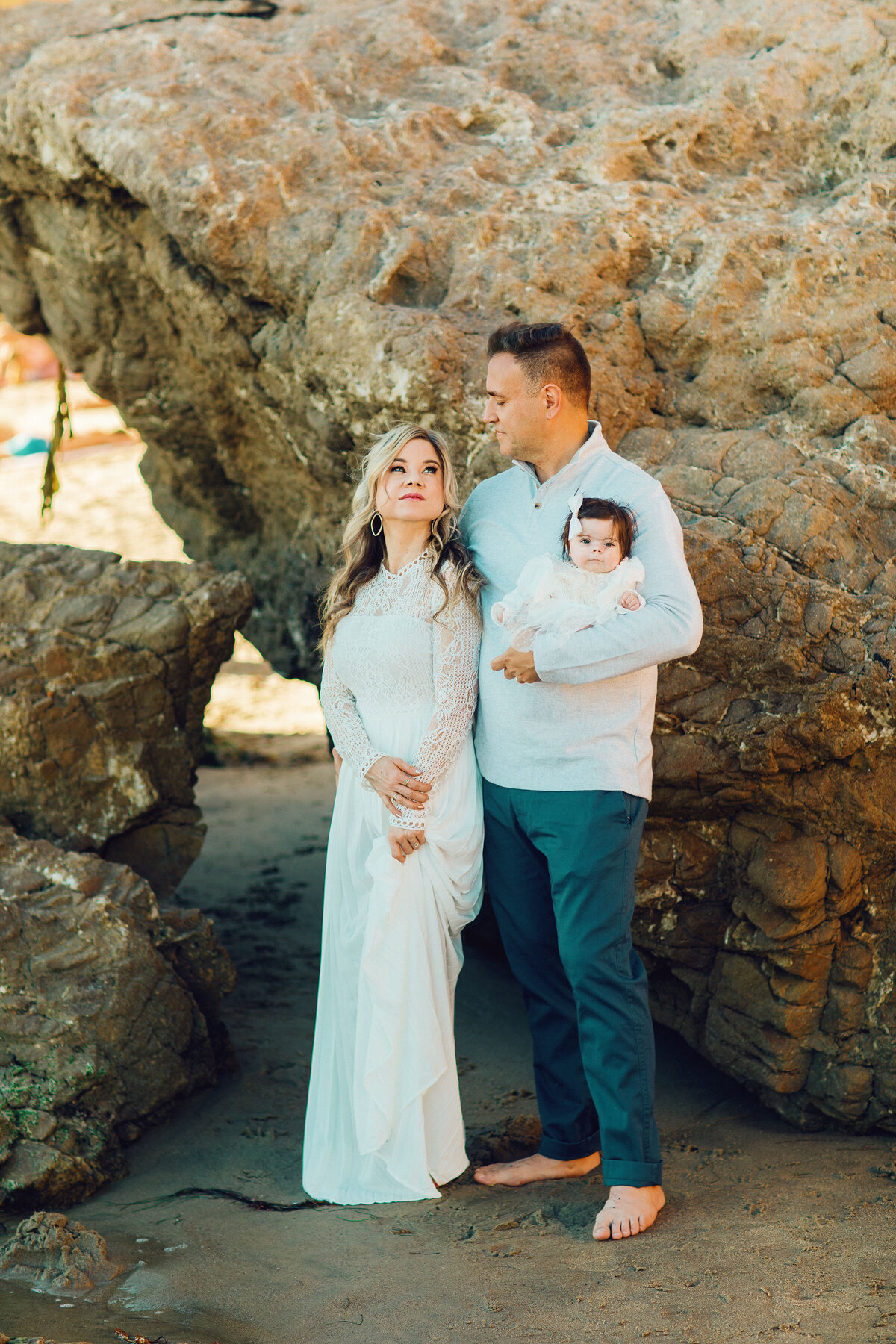 Family Portrait Photo Of Couple Standing Beside a Rock With Their Baby Los Angeles
