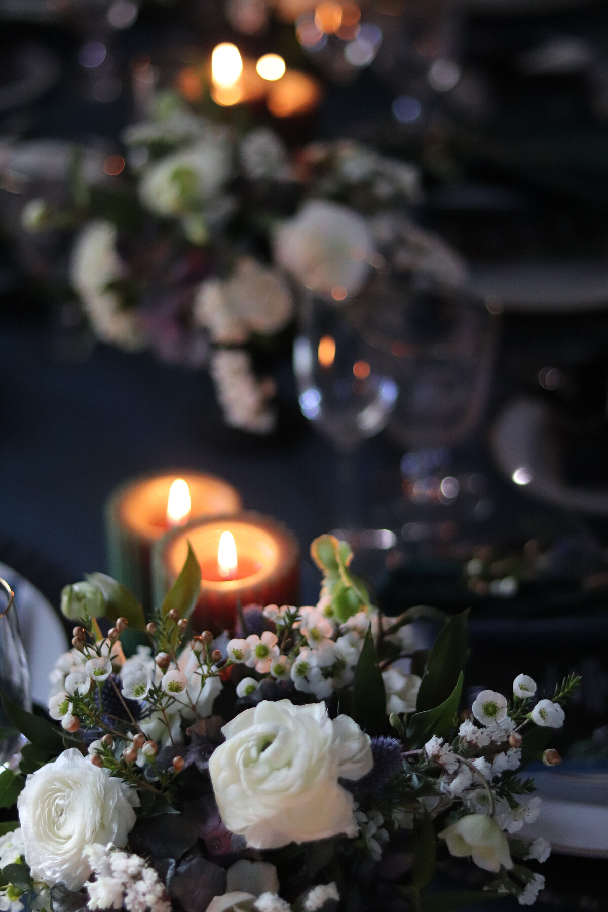 A navy blue black white and green wedding reception table with candles and flowers