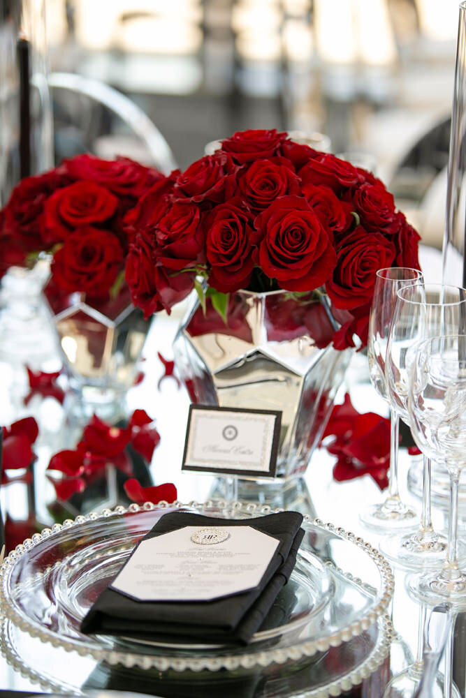 A plate set up with bouquets of red rosed behind them