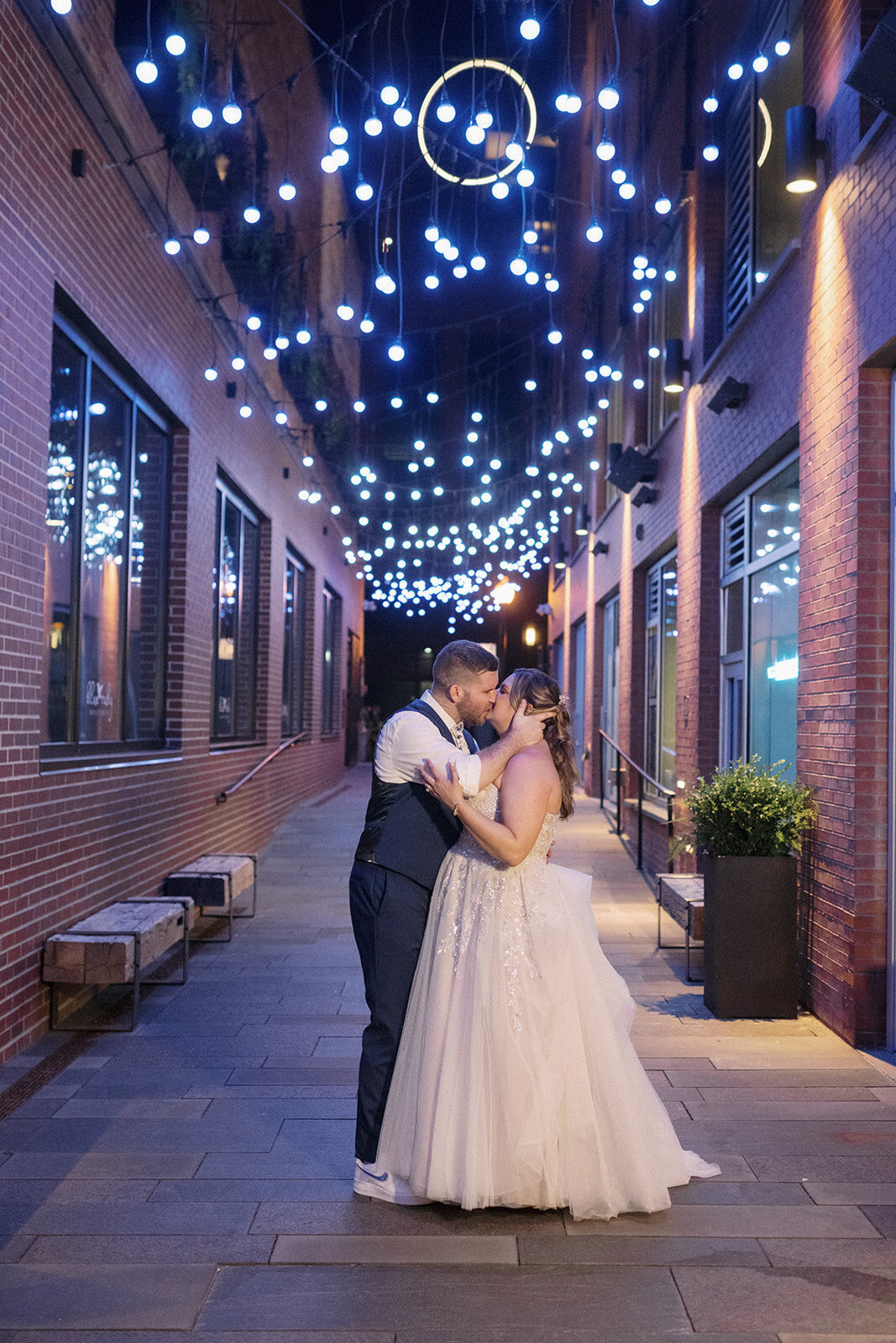 Bride and groom share a kiss under the lights at the Dairy Block in Denver, Colorado.