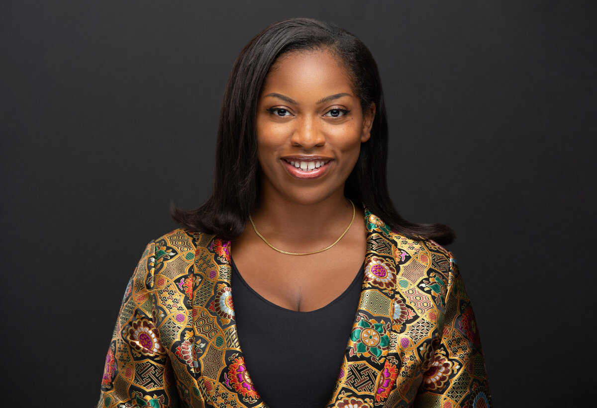 African American black female lawyer woman poses on a dark grey background for a professional headshot and personal branding photo at by Janel Lee Photography in Cincinnati Ohio