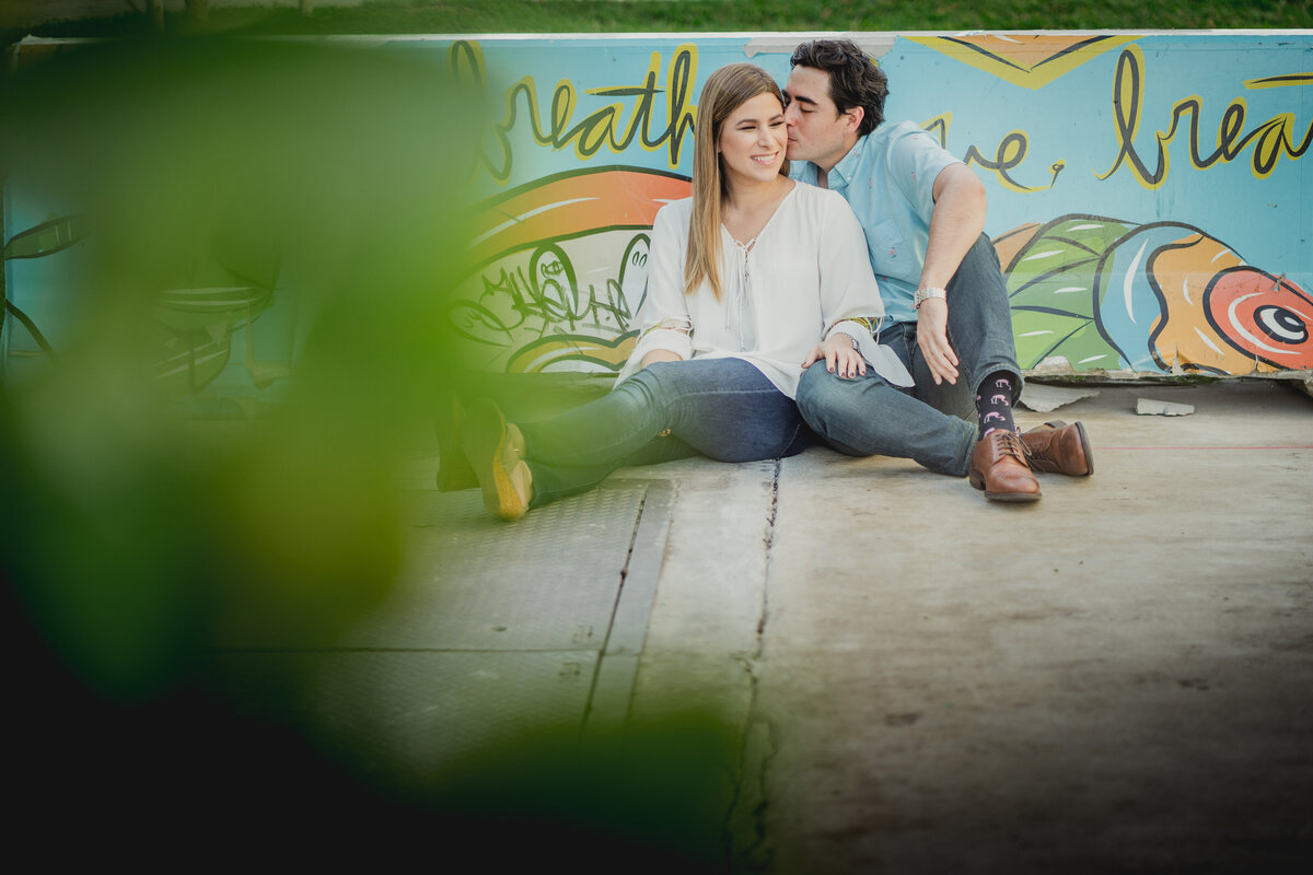 A couple sitting by a colorful "breathe" mural in Miami, Florida, sharing a sweet and intimate moment.