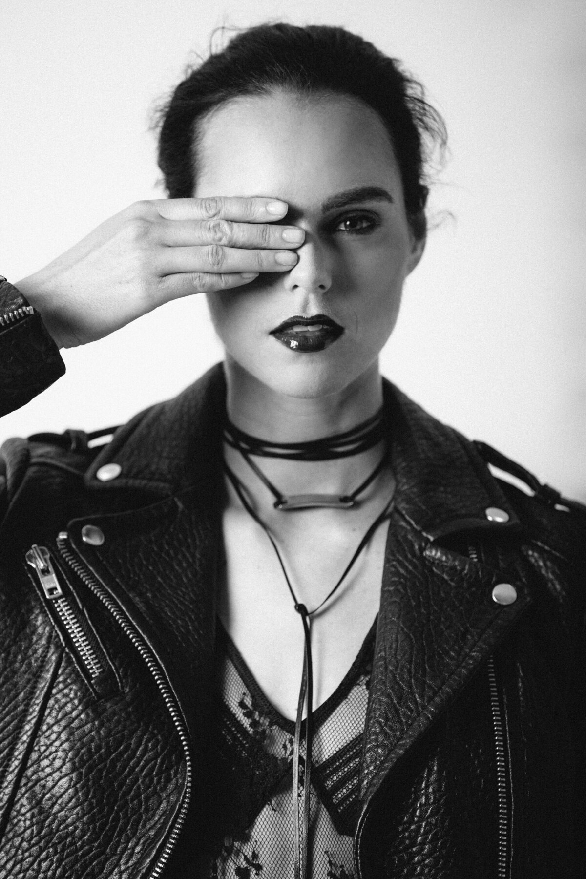 Picture of girl in black leather jacket covering her right eye