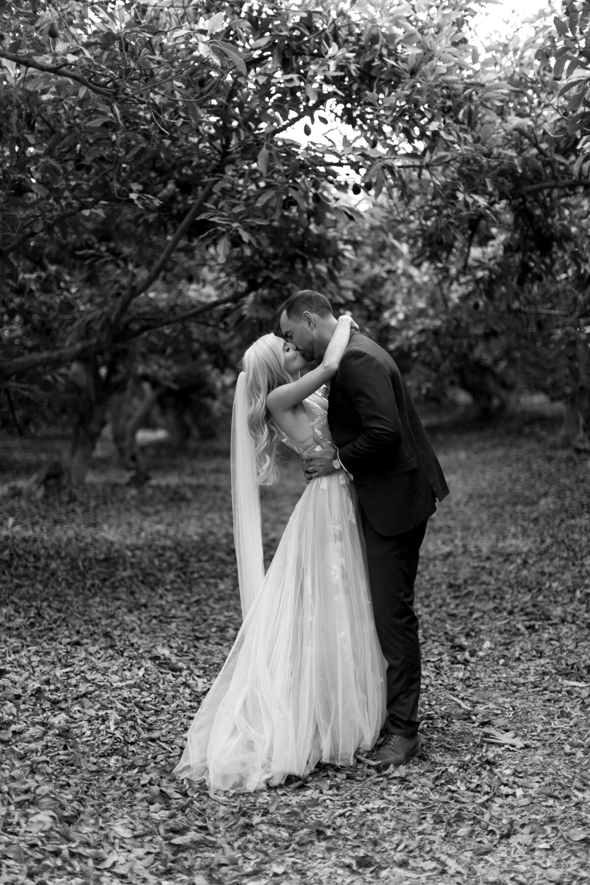 Bride and groom kissing surrounded by trees and nature