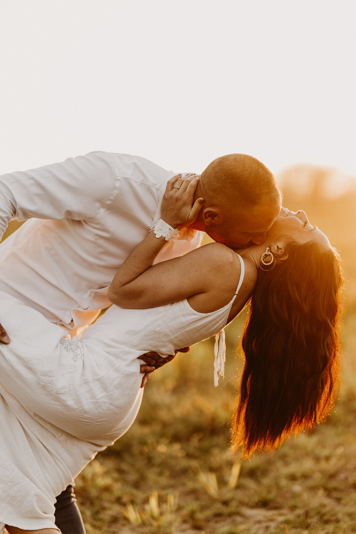 Femme serrant son compagnon de dos sur une plage au coucher du soleil. Moment capturé par Laura, photographe couple en Vendée.