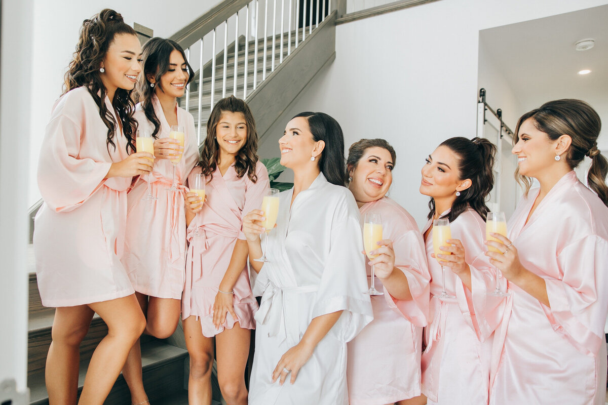 Bridesmaids cheers mimosas while wearing matching pink robes