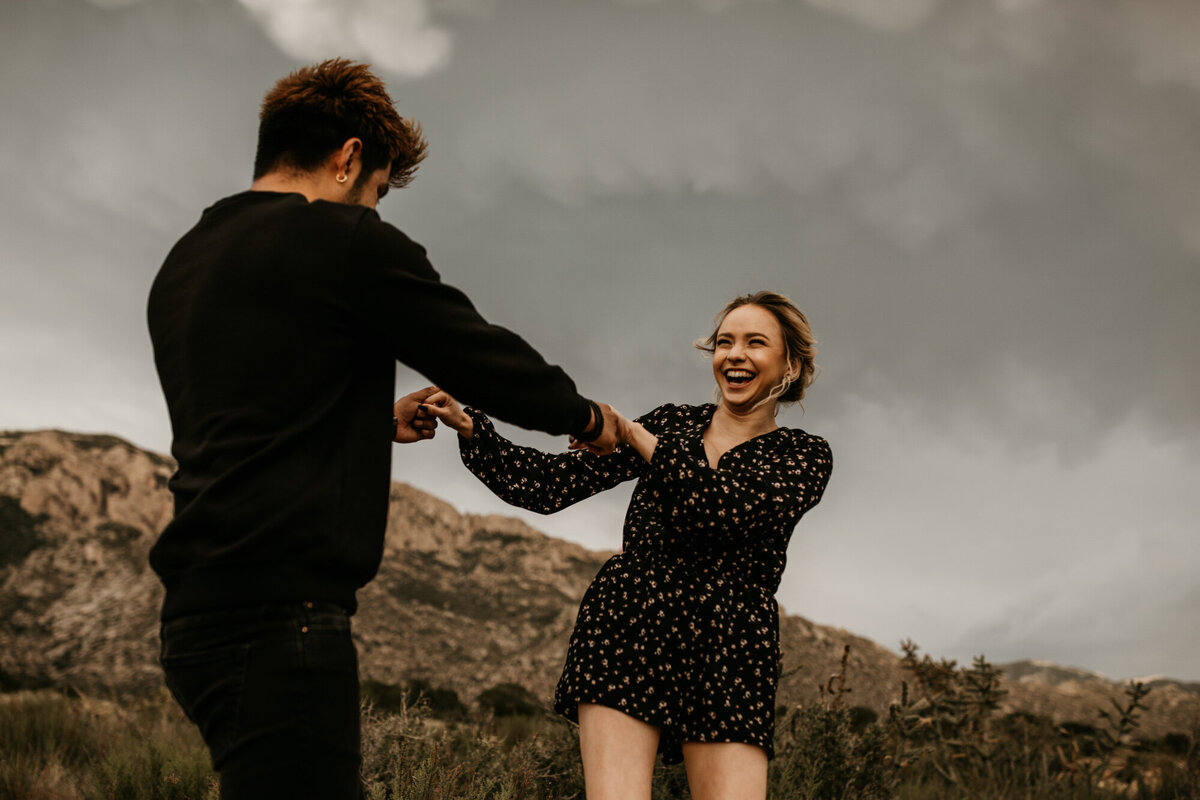 engaged couple holding hands spinning in the desert